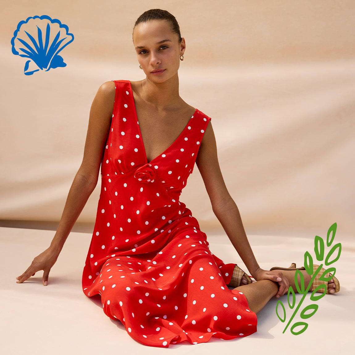 Woman wearing a red polka dot dress sitting on a beige background with a brand logo and green leaf symbol.