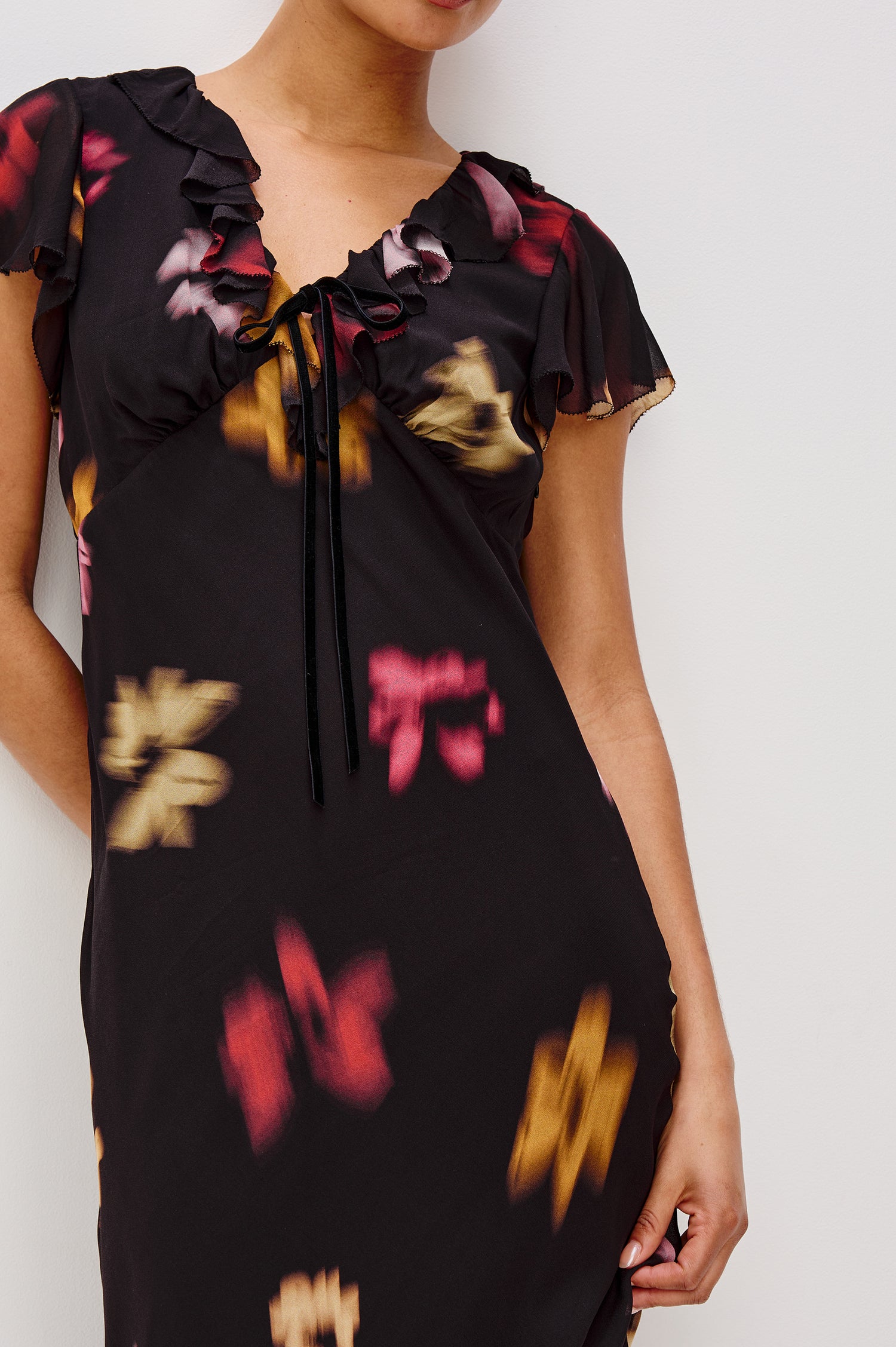Neela Midi Dress in Chiffon With Ruffle V-Neckline, Center Front Self-Ties, Ruffled Cap Sleeves, and Empire Waistline in Blurred Floral Colorway - Upper Body Front Close Up View Featured on Model