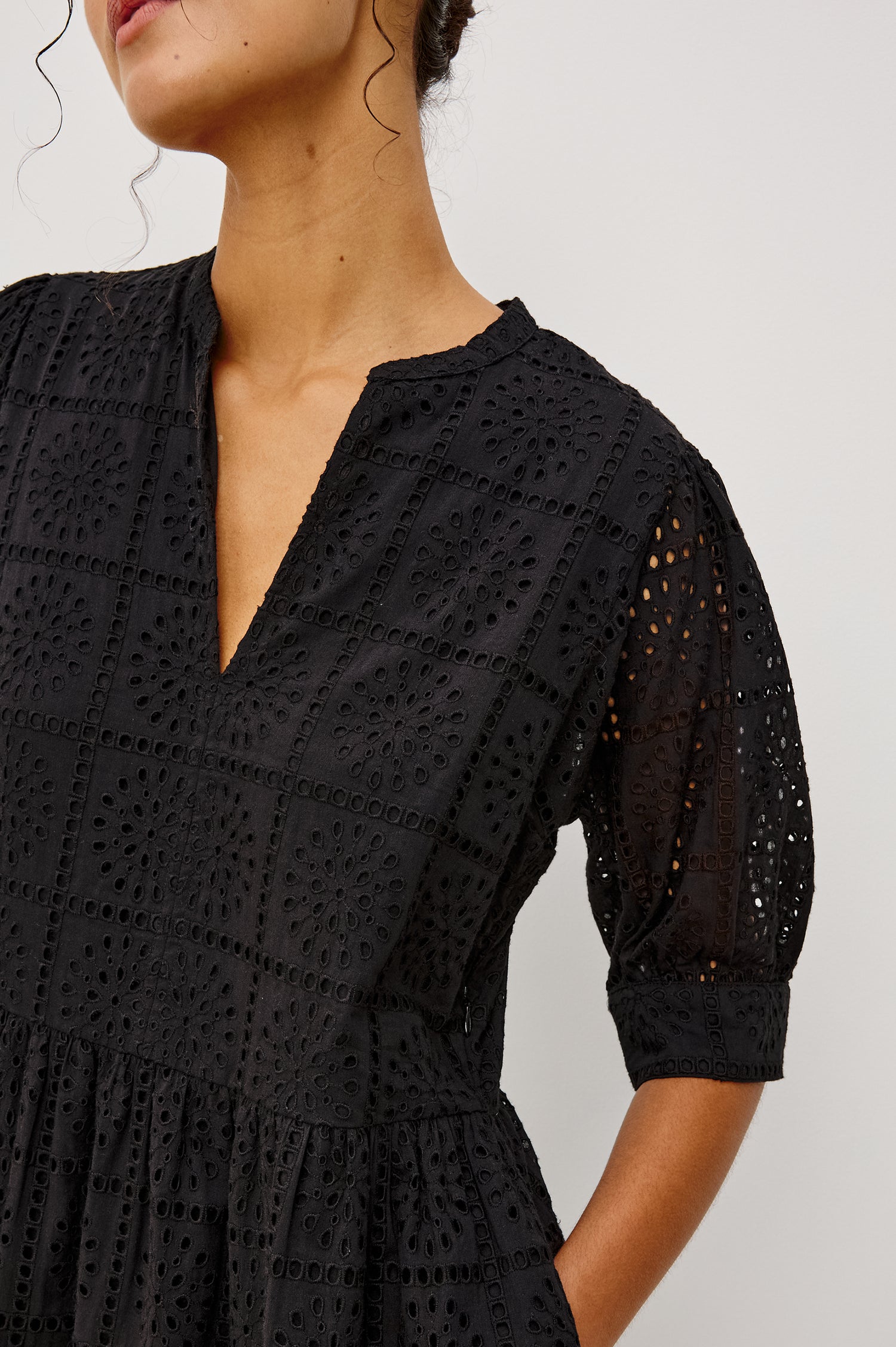 Nella Smock Maxi Dress in Cotton With Grid Eyelet Embroidery Lined Body Split Band V-Neckline Drop Waist Gathered Skirt and Short Puff Sleeves With Fitted Cuffs in Black Colorway - Upper Body Close Up Front View Featured on Model