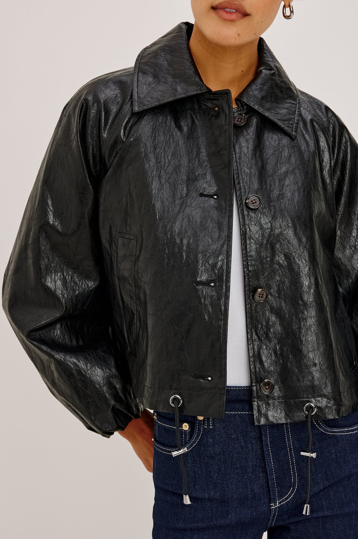 North Jacket in Vegan Leather With Cropped, Boxy Fit, Drawcord Hem, Oversized Collar, Front Buttons, and Welt Pockets in Black Colorway - Upper Body Front Detail View Featured on Model.