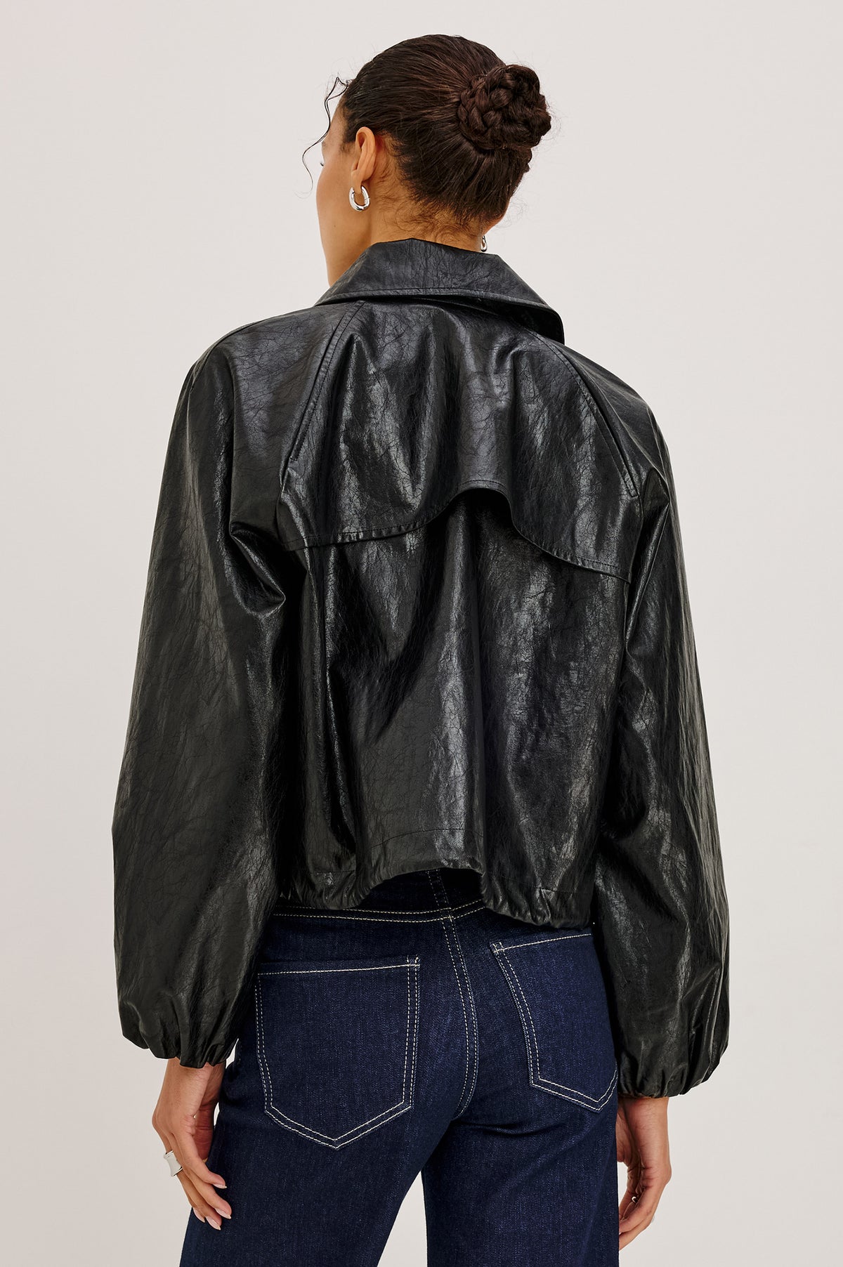 North Jacket in Vegan Leather With Cropped, Boxy Fit, Drawcord Hem, Oversized Collar, Front Buttons, and Welt Pockets in Black Colorway - Upper Body Back View Featured on Model.