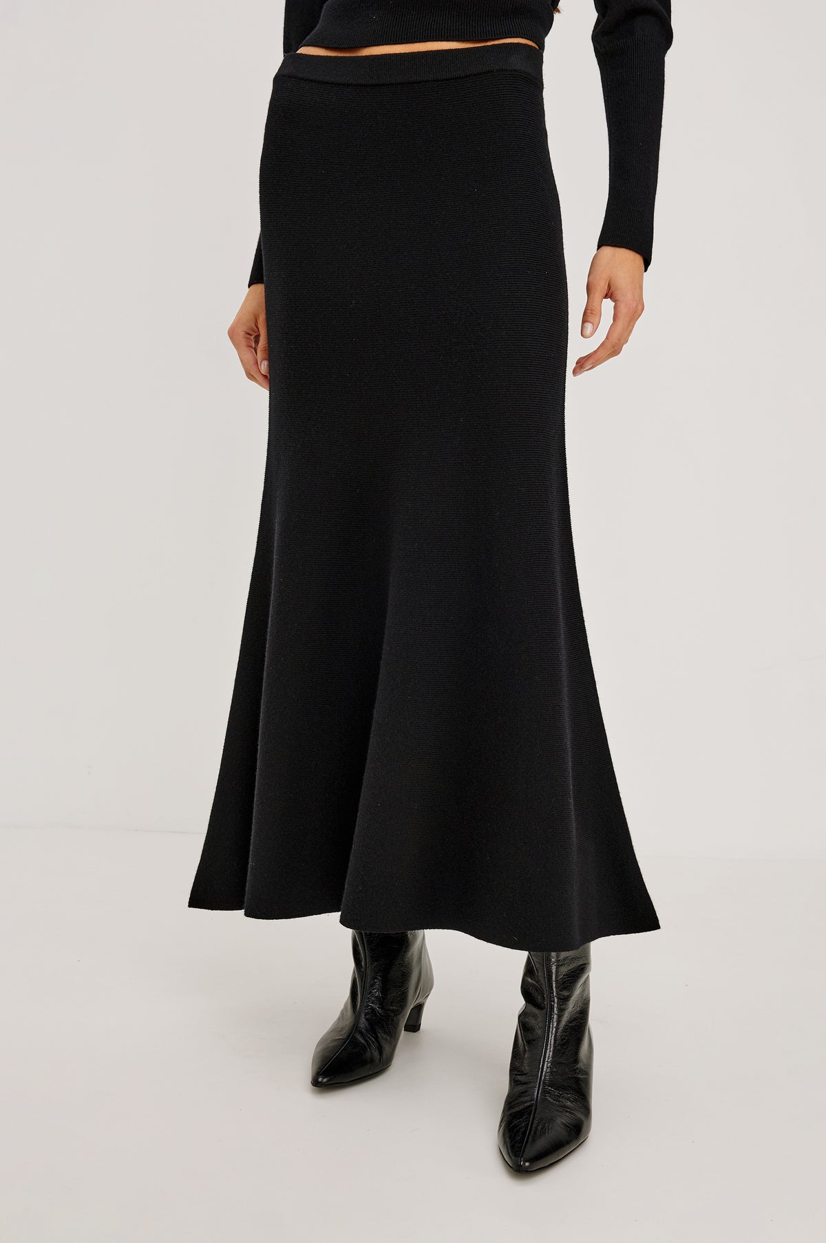 Odita Maxi Skirt in Soft Ribbed Wool Blend Knit With Elastic Waist, and A-Line Silhouette in Black Colorway - Crop Front View Featured on Model.