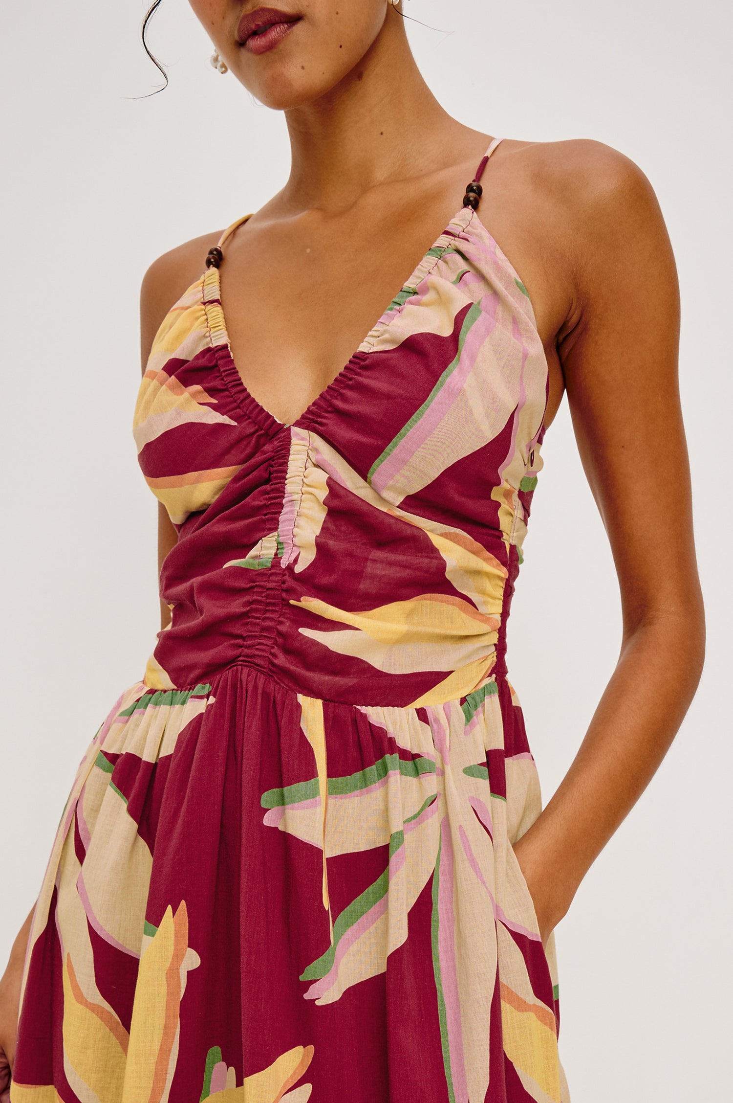 Palm Maxi Dress in Beach Cotton WIth Fitted Shirred Bodice V-Neckline Adjustable Shoulder Straps With Wooden Bead Detailing and Tiered Skirt in Red Palma Colorway - Upper Body Close Up Front View Featured on Model