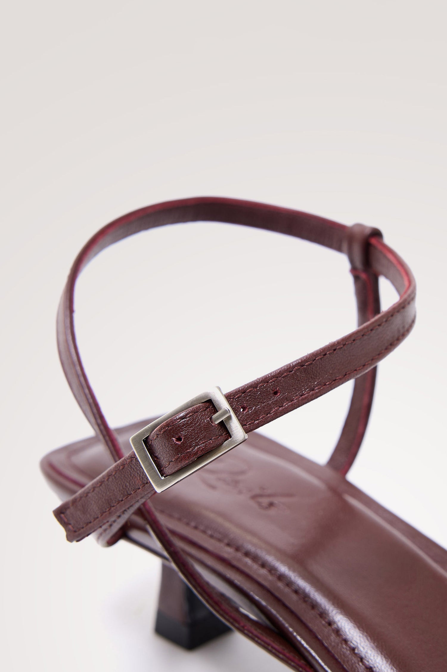 Palma Sandal Heel in Top-Grain Leather With Single Toe Strap, Adjustable Buckled Wrap Ankle Strap, and Low Heel in Burgundy Colorway - close-up view of shoe strap.