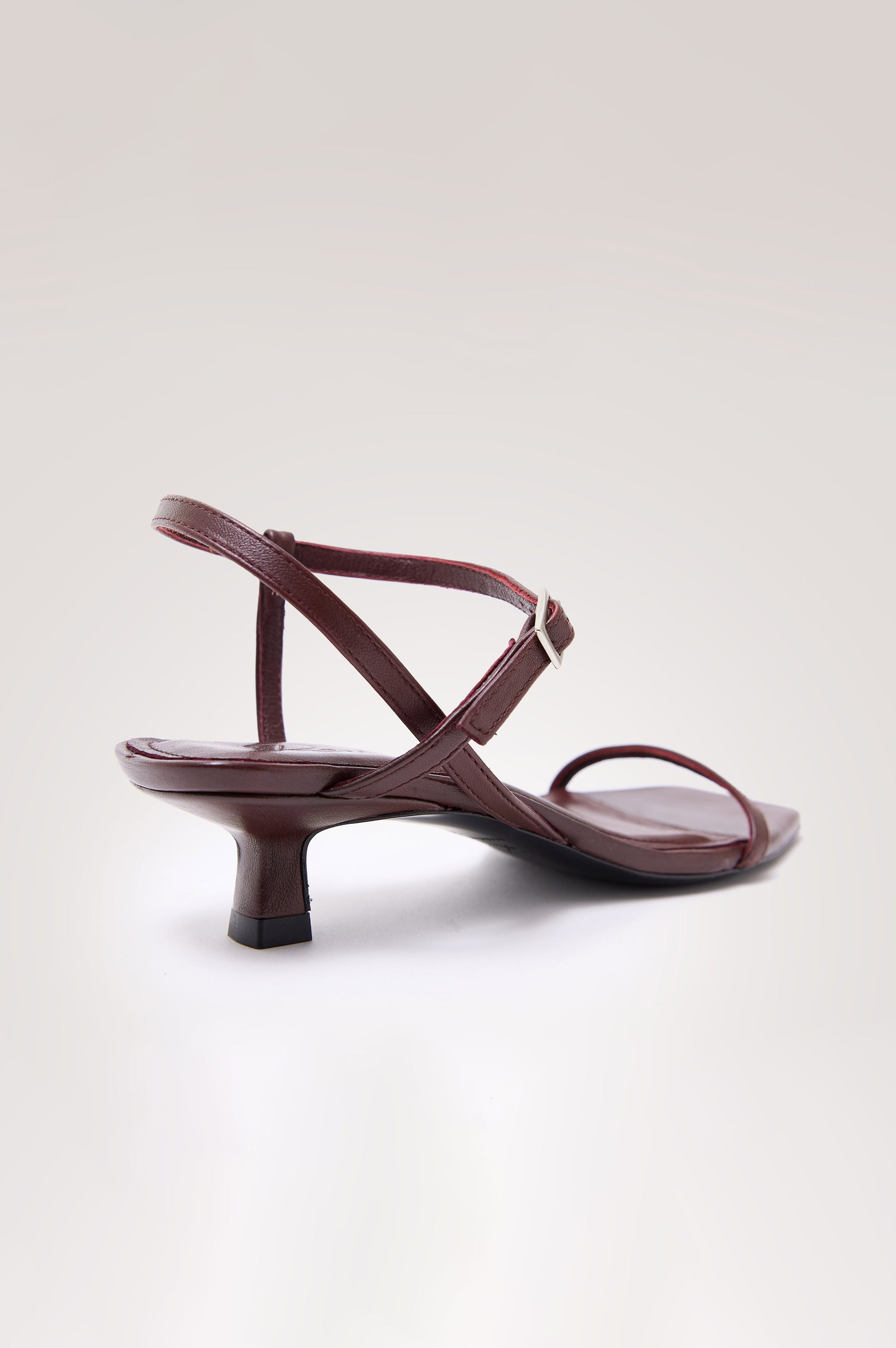 Palma Sandal Heel in Top-Grain Leather With Single Toe Strap, Adjustable Buckled Wrap Ankle Strap, and Low Heel in Burgundy Colorway - angeled back view of shoe.