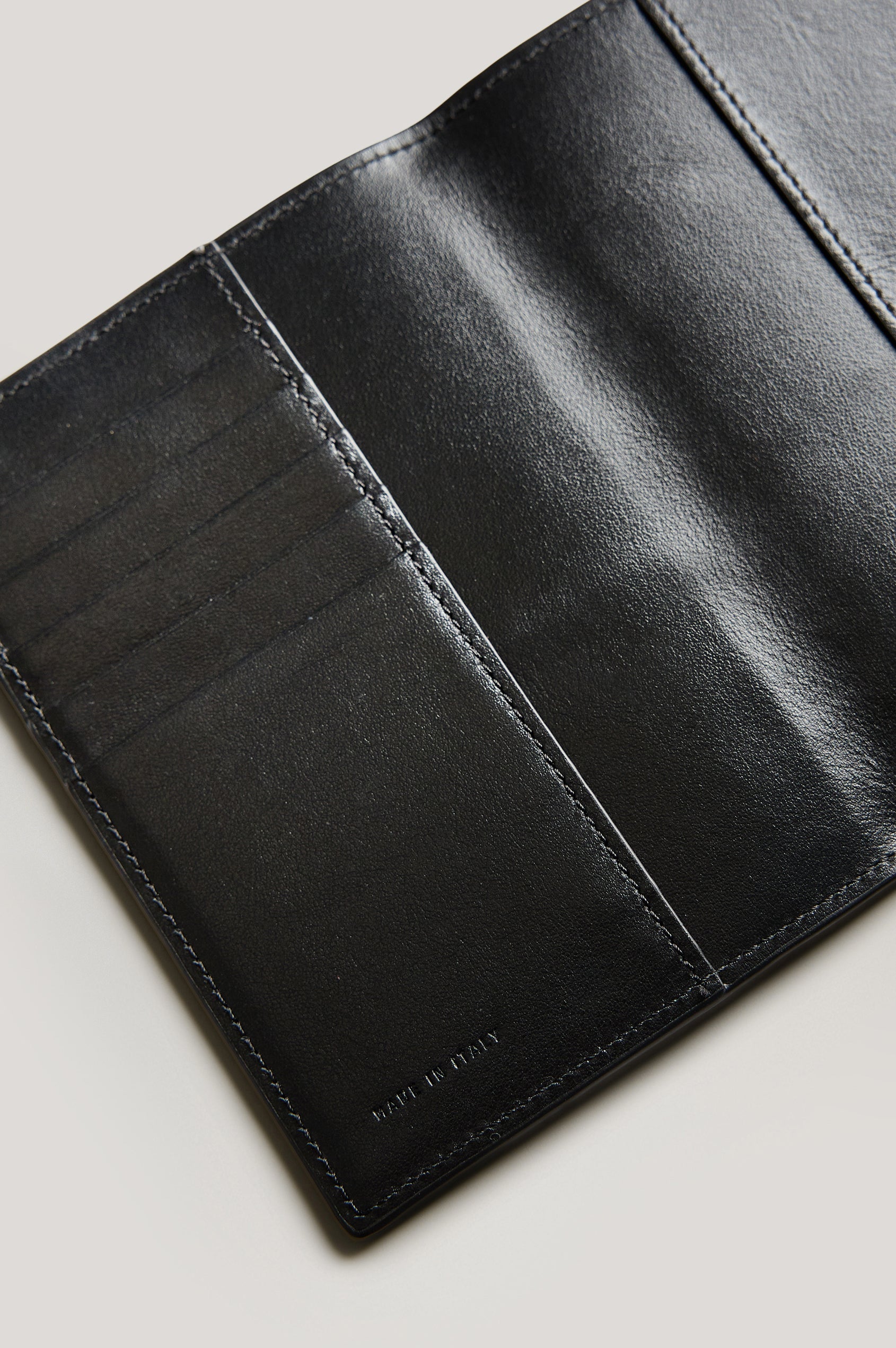 Leather passport holder opened, close up inside view, in Black colorway.