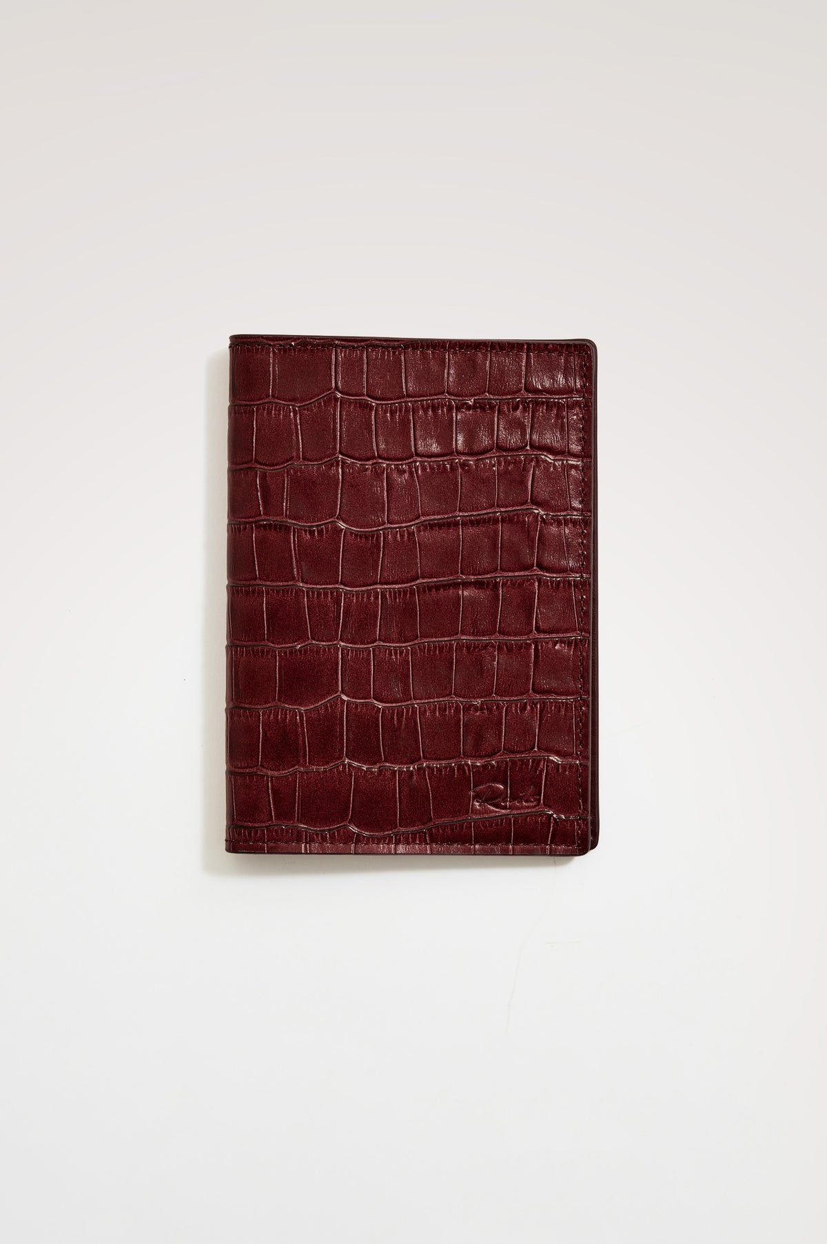 Passport Holder in Croc-Embossed Spanish Leather With Five Card Slots, Two Side Pockets, and Embossed Rails Logo in Burgundy Croc Embossed Colorway - Front view flatlay featured.
