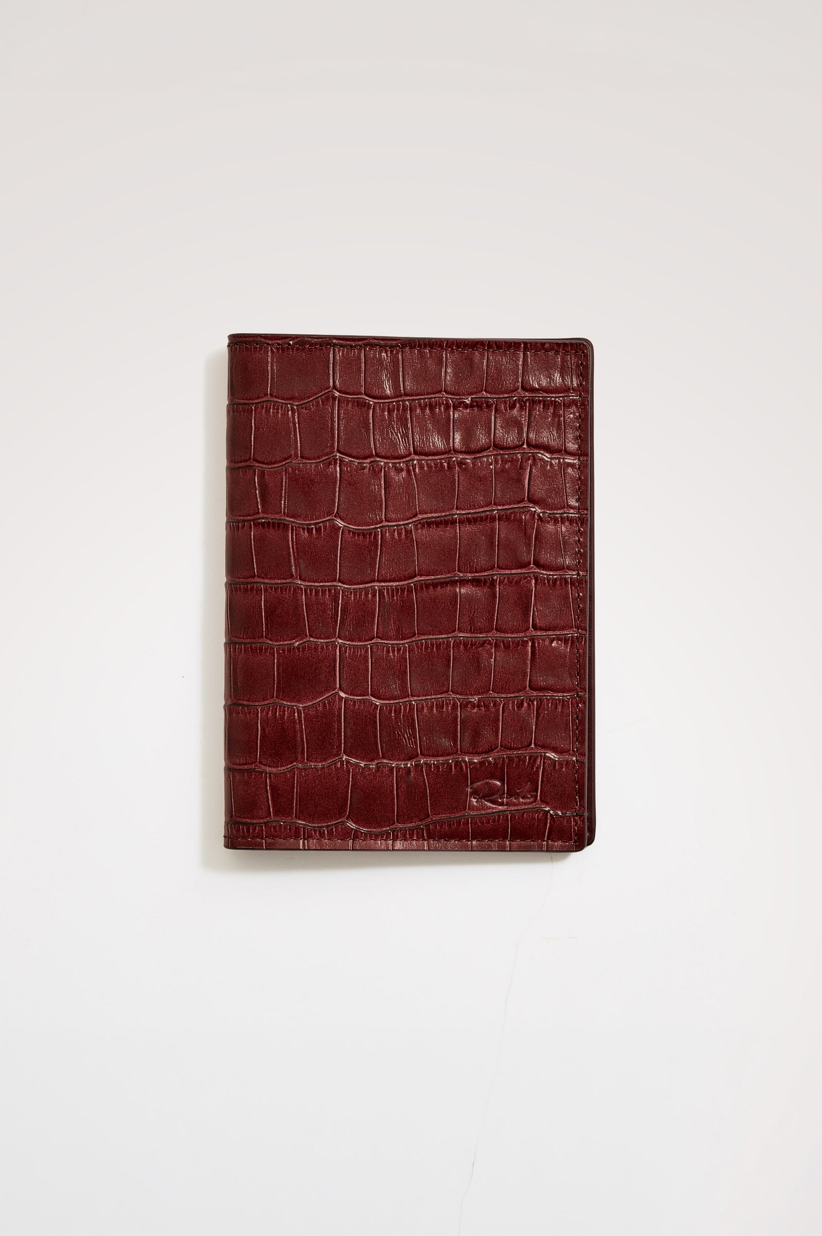 Passport Holder in Croc-Embossed Spanish Leather With Five Card Slots, Two Side Pockets, and Embossed Rails Logo in Burgundy Croc Embossed Colorway - Front view flatlay featured.