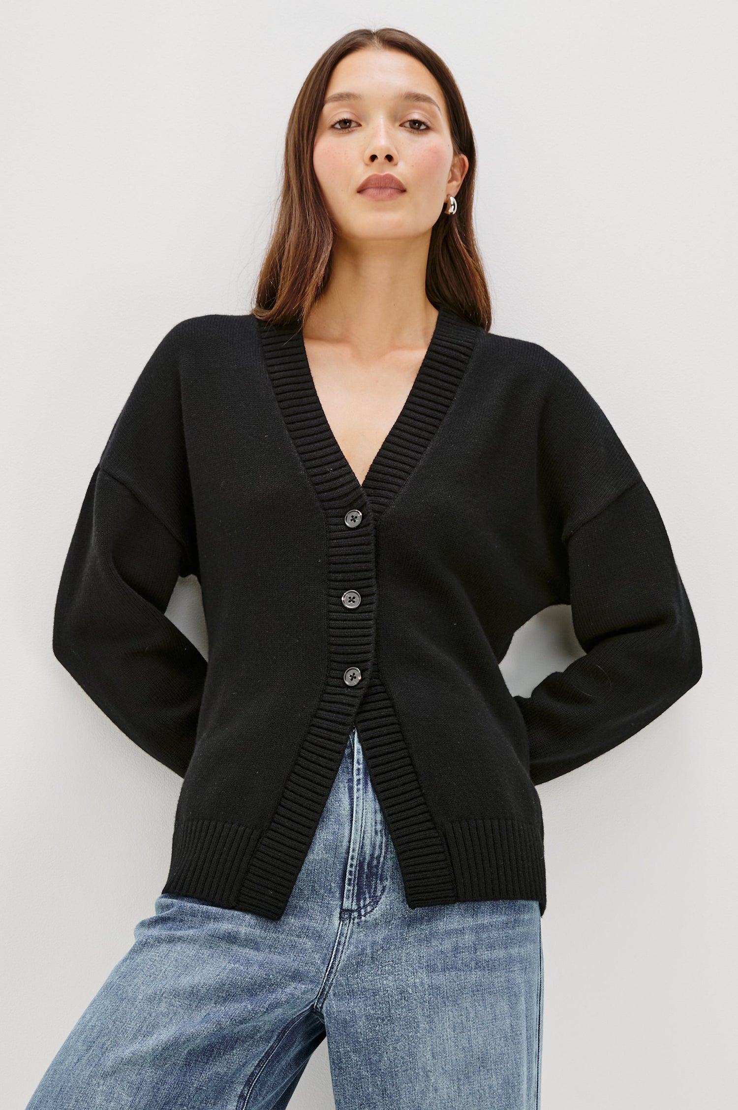 Longline cardigan in a cotton-wool blend in Black Colorway. The design features drop shoulders and a front cutaway detail, creating a soft, relaxed, and flattering silhouette. Front View on Model.