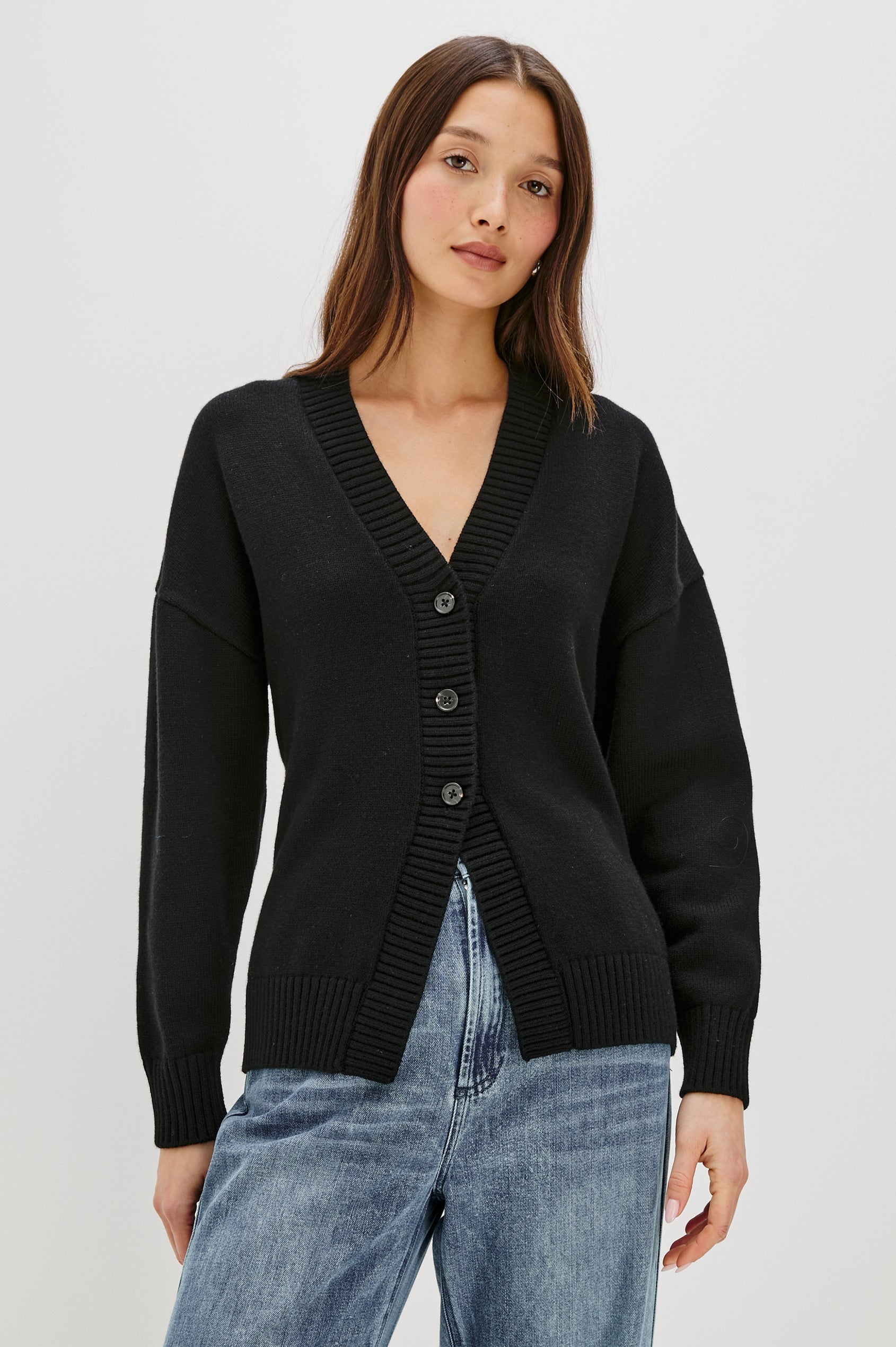 Longline cardigan in a cotton-wool blend in Black Colorway. The design features drop shoulders and a front cutaway detail, creating a soft, relaxed, and flattering silhouette. Front View on Model.