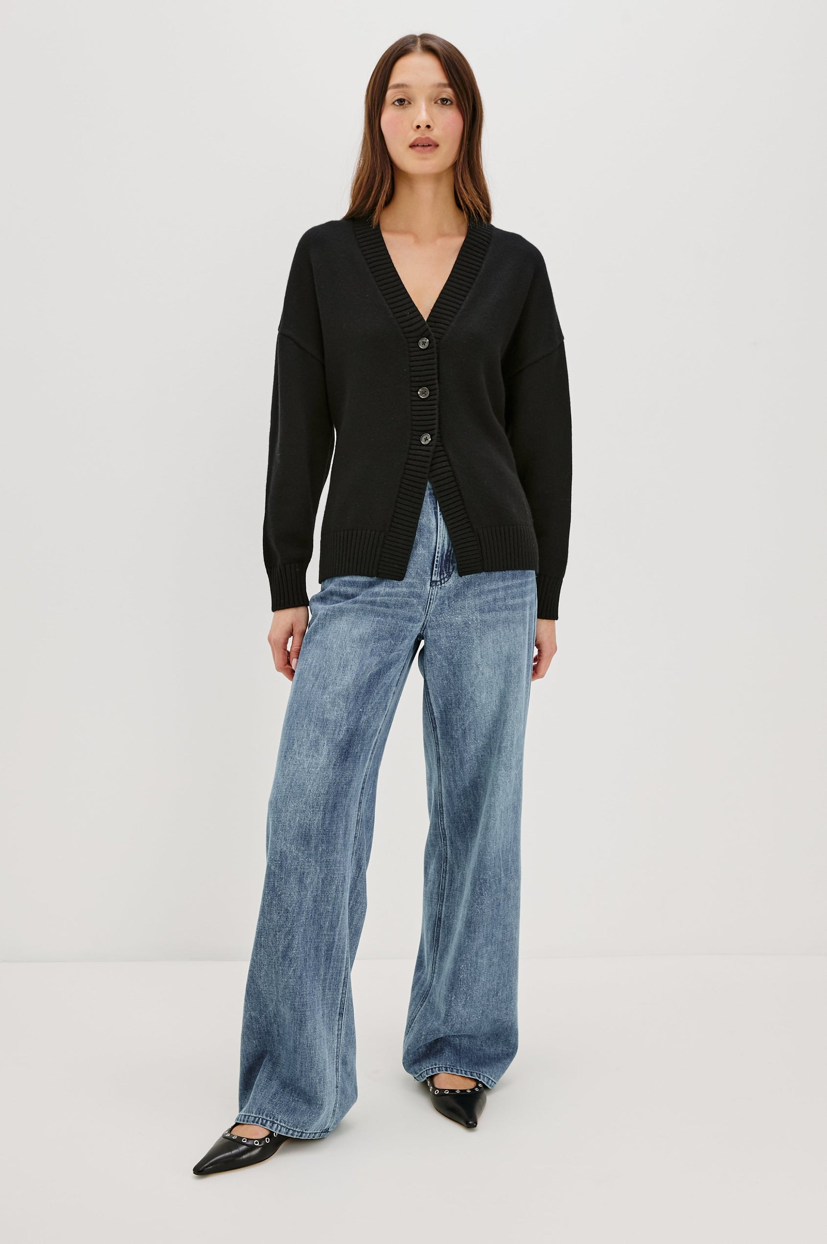 Longline cardigan in a cotton-wool blend in Black Colorway. The design features drop shoulders and a front cutaway detail, creating a soft, relaxed, and flattering silhouette. Full Body Front View on Model.