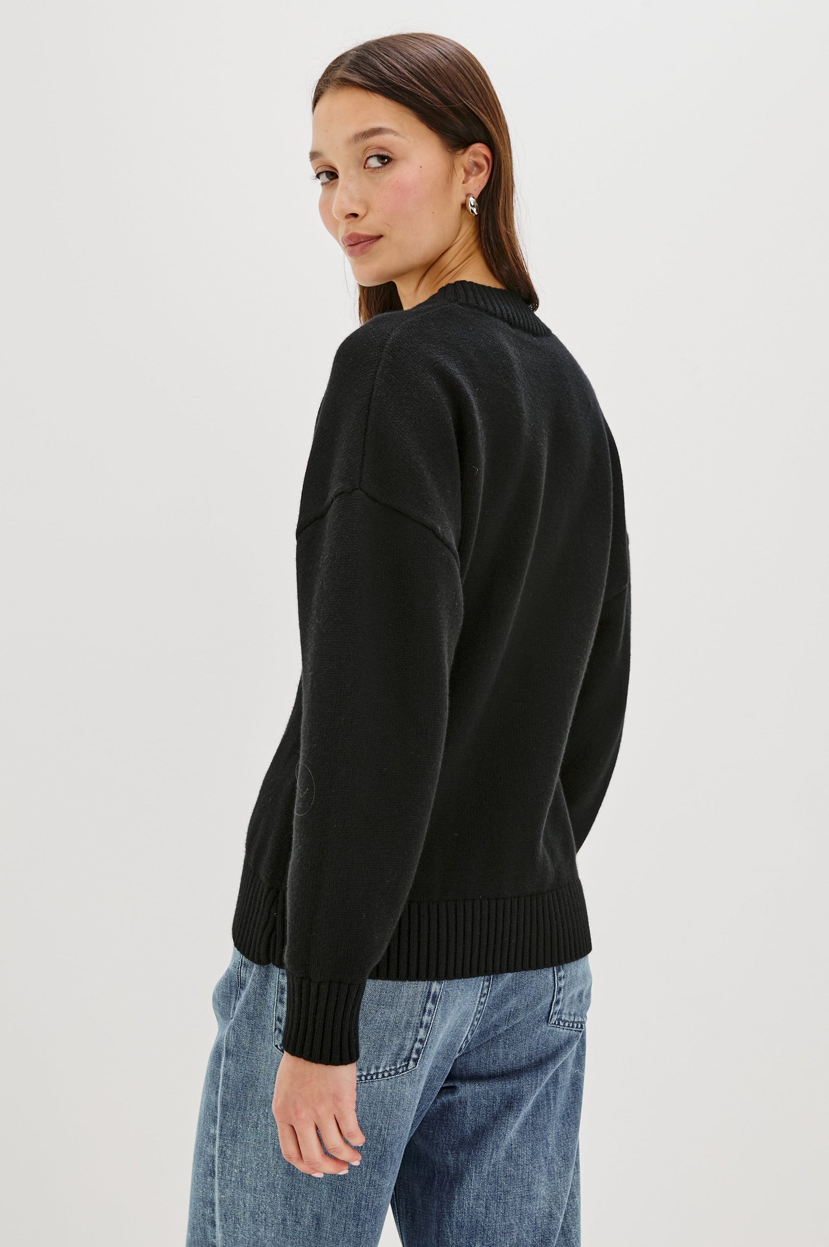 Longline cardigan in a cotton-wool blend in Black Colorway. The design features drop shoulders and a front cutaway detail, creating a soft, relaxed, and flattering silhouette. Back View on Model.