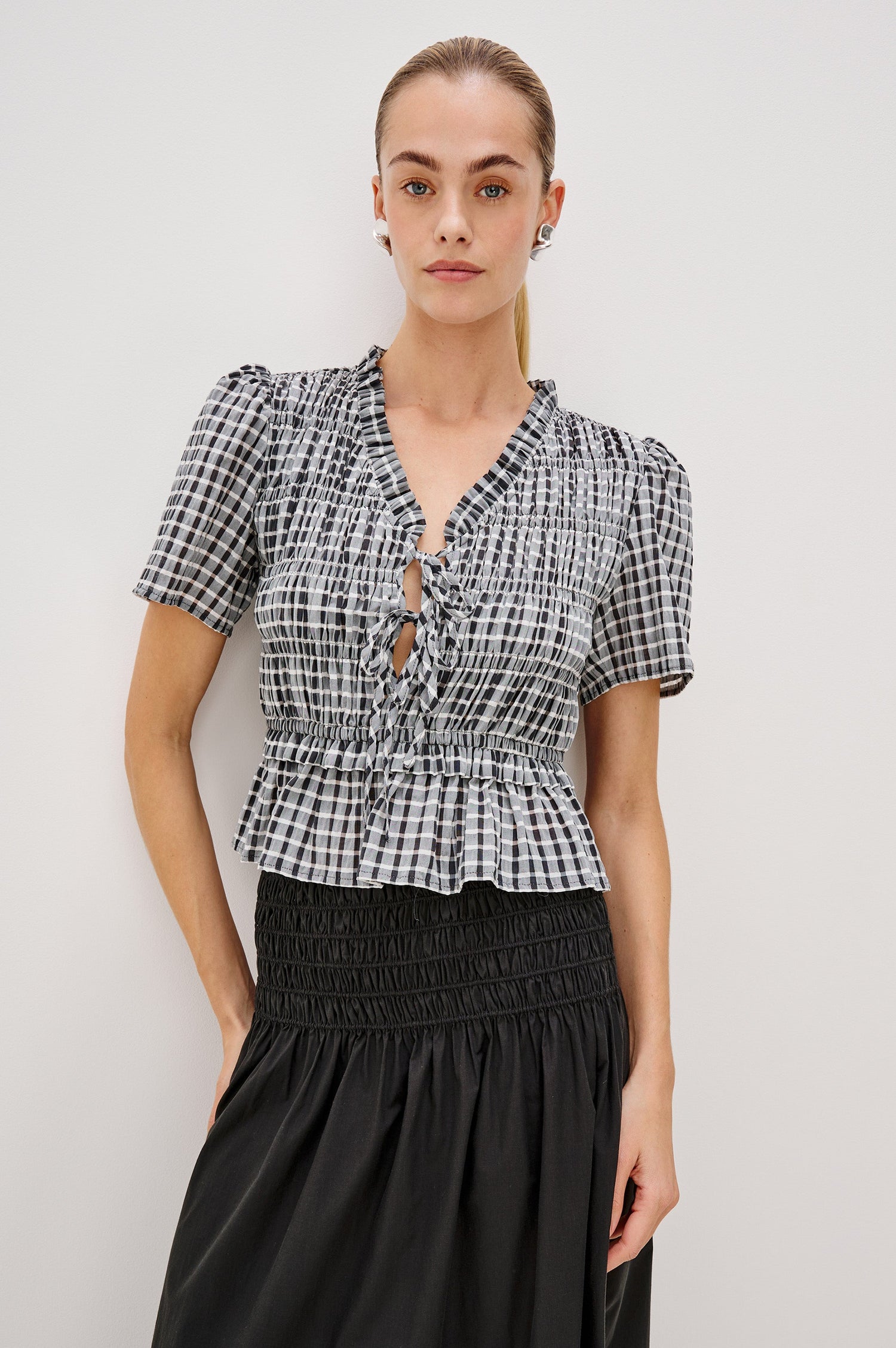 Portia V-Neck Tie Front Top with Short Puff Sleeves and a Ruffled Peplum Hem in Ash Seersucker Colorway. Front View Shown on Model.