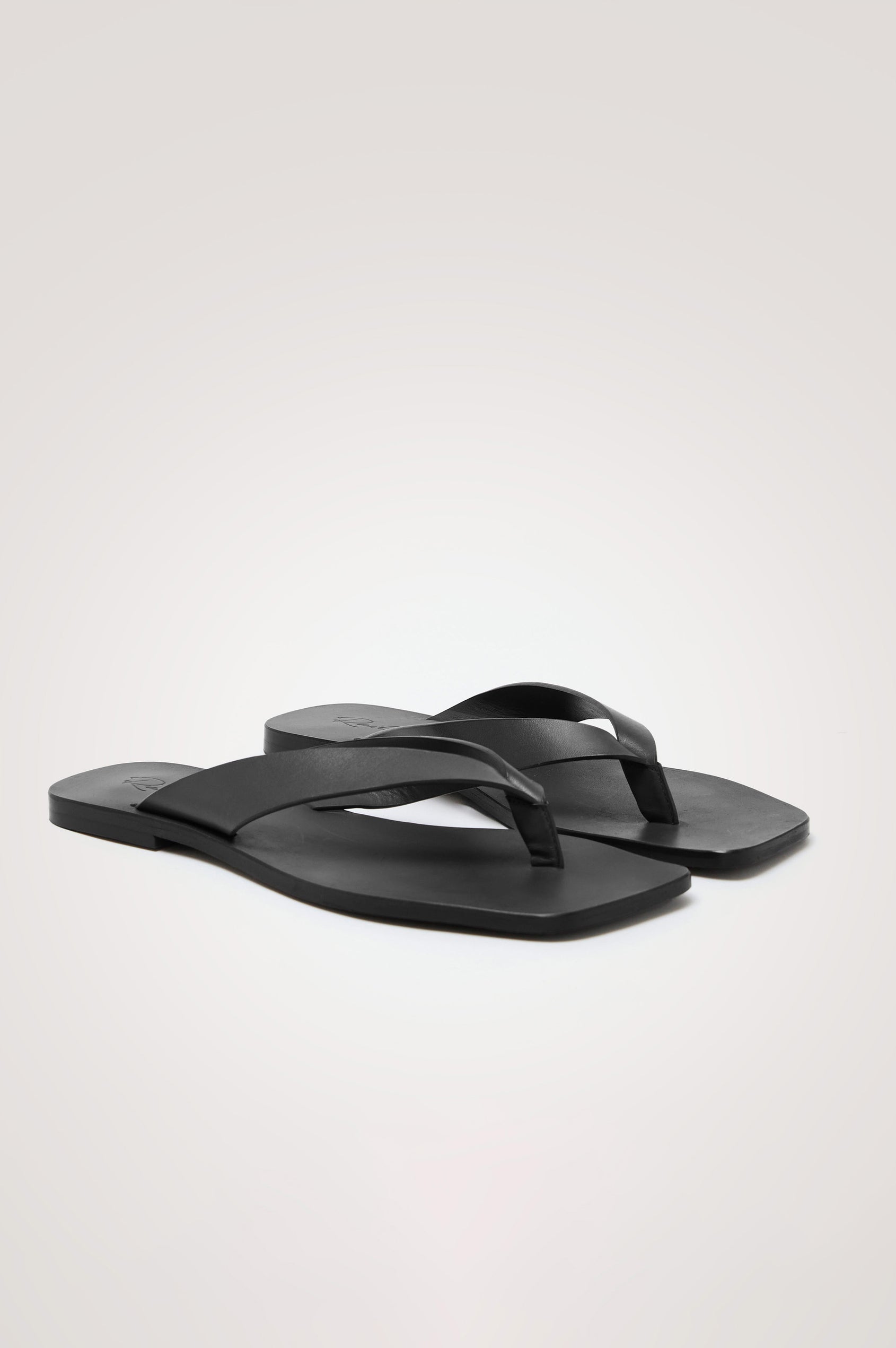 Porto Thong Sandal in Leather With Square Toe and Cushioned Footbed With Branded Embossed Detail in Black Colorway - Front Angled View Featured on Model
