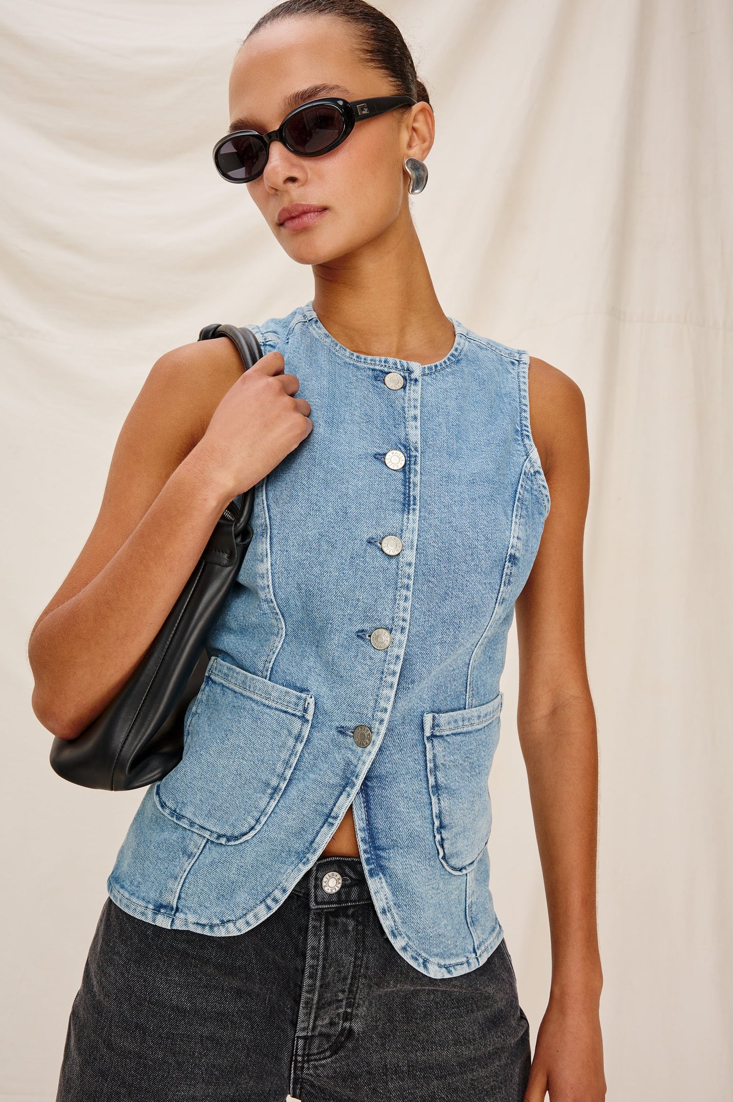 Portola Sleeveless Denim Vest with Exposed Button Front Closure, Crew Neck, Front Patch Pockets and a Scalloped Split Hem in Blue Eyed Girl Colorway. Full Body Front View Shown on Model.
