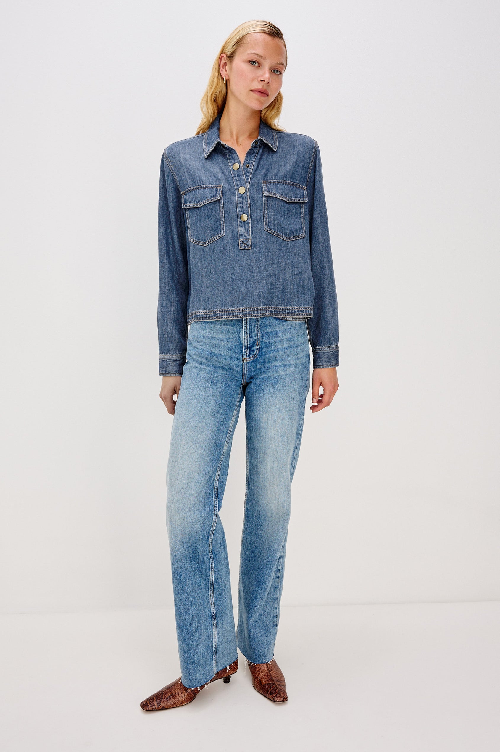 Ports is a soft, lightweight denim shirt with a cropped fit. The shirt features a half placket with snap-front closures, short sleeves, and two chest pockets in Antique Blue Colorway - Full Body Front View on Model
