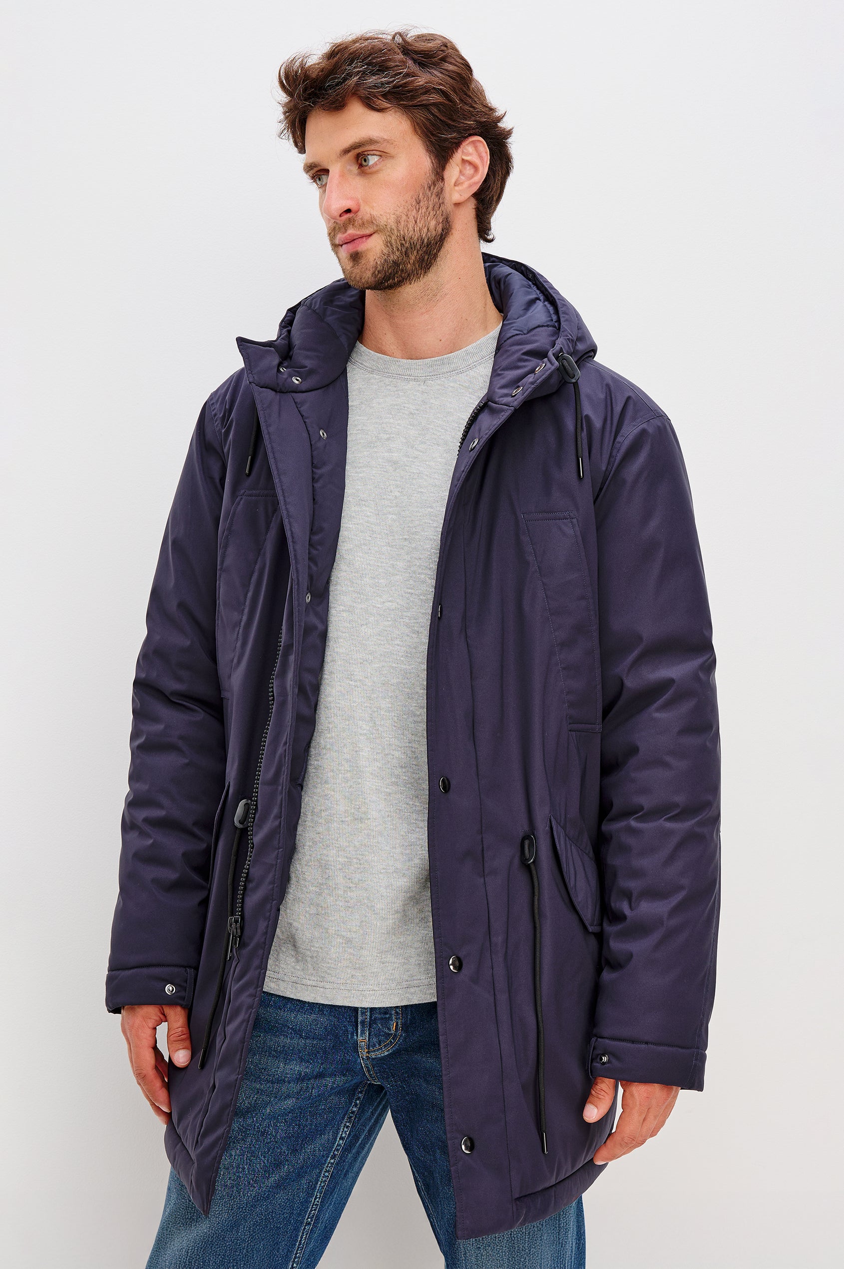 Rainier is a hooded parka coat, water-resistant and features hand warming pockets with snap closure, drawcord at hood and waist for sinching effect and a double flap center front closure and back seam vent in Navy colorway. Back view featured on model.