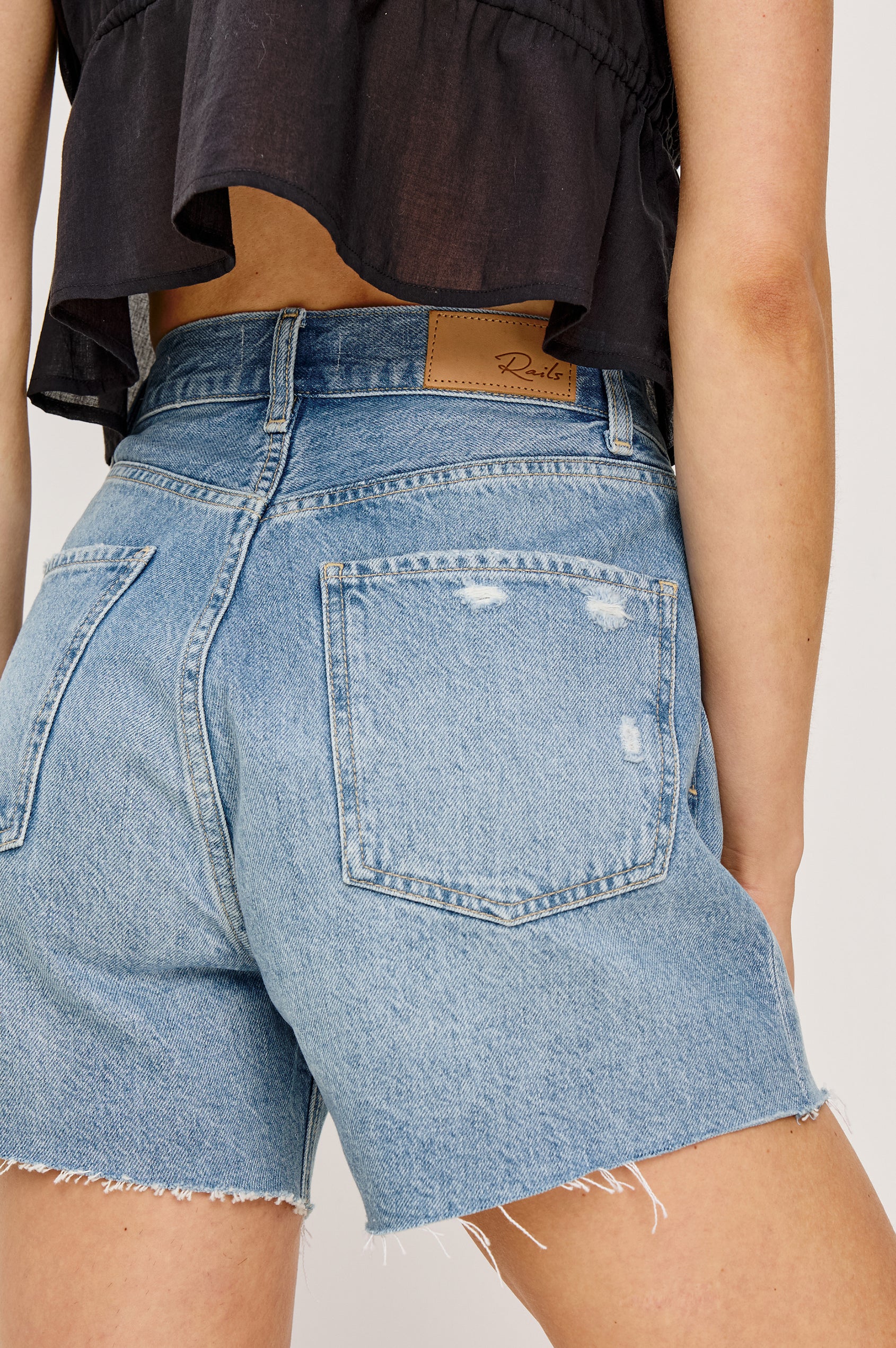 Rancho is a 5-pkt, high rise denim short in Crystal Cove colorway. Close up back view featured on model.