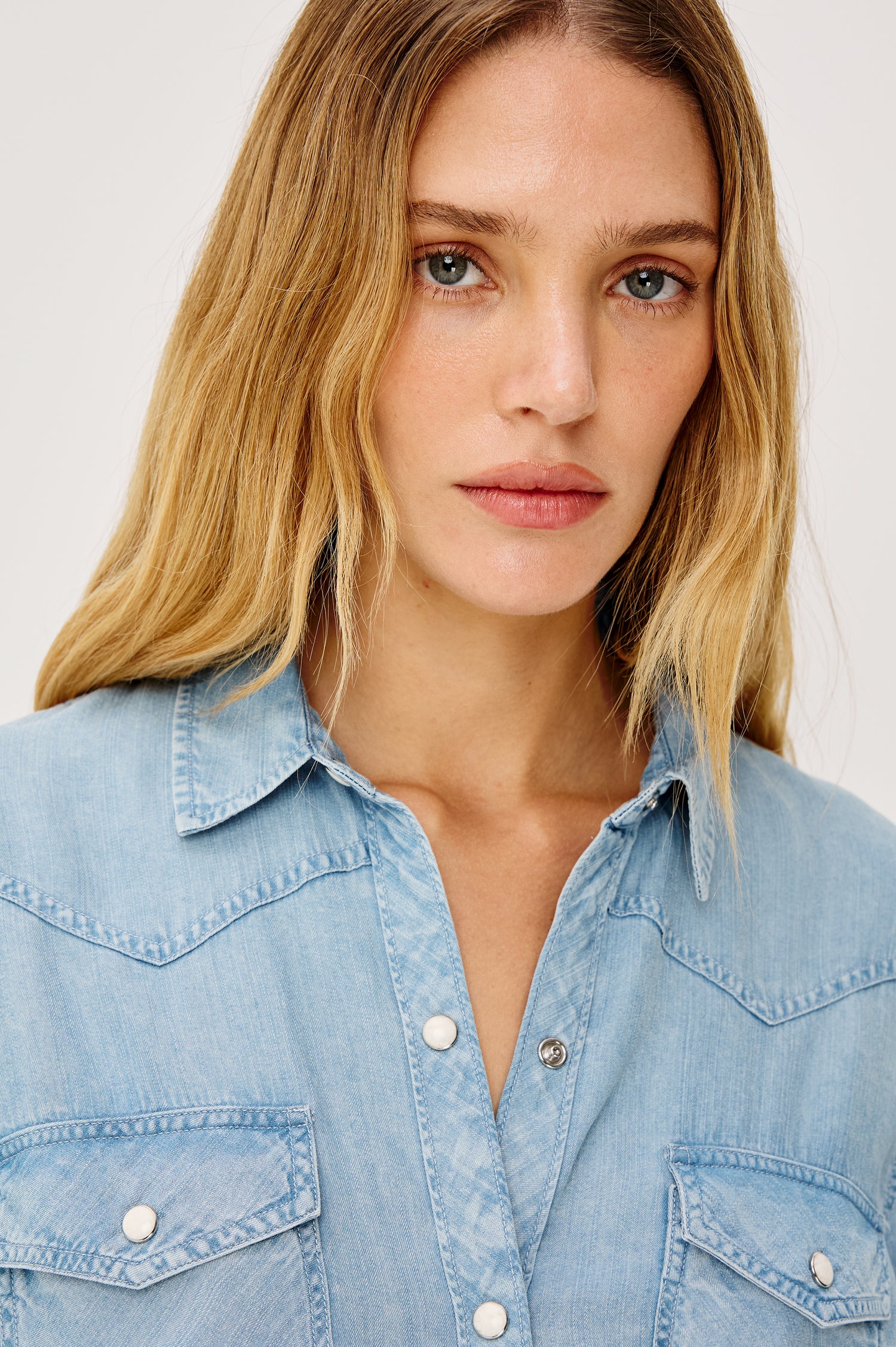 Remi is a utility-style Tencel denim shirt with a relaxed fit. The shirt features a notched collar, two front flap pockets, and faux horn buttons etched with a logo in medium indigo colorway - Front View Featured on Model
