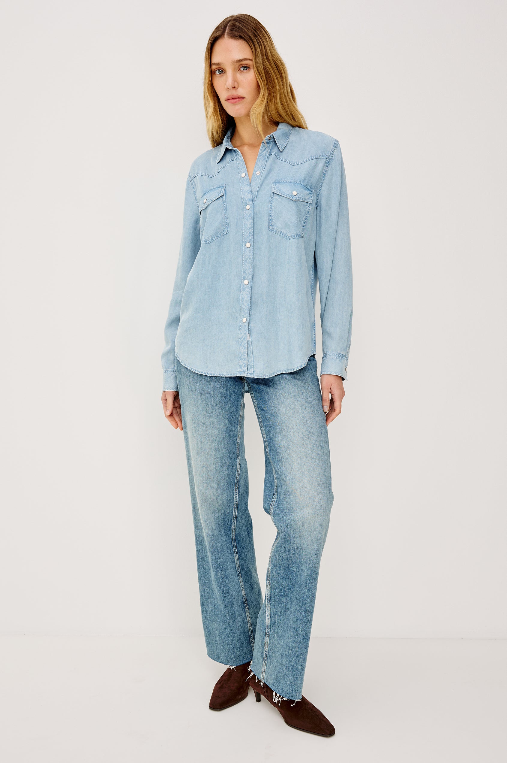 Remi is a utility-style Tencel denim shirt with a relaxed fit. The shirt features a notched collar, two front flap pockets, and faux horn buttons etched with a logo in medium indigo colorway - Front View Featured on Model