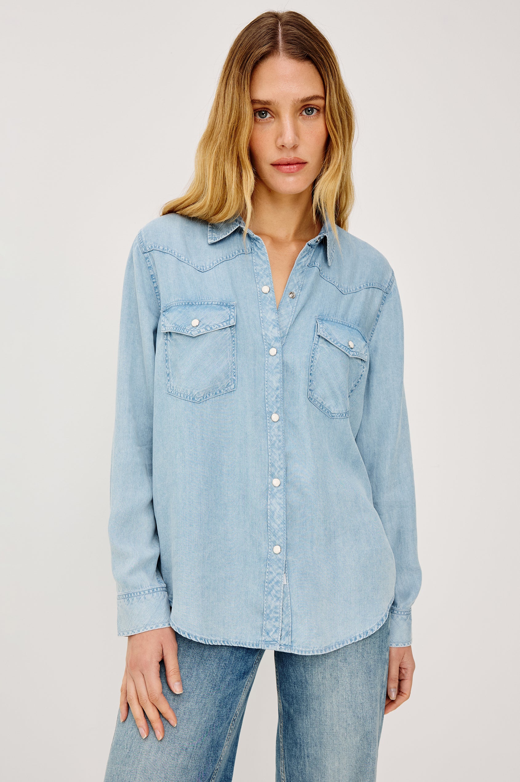 Remi is a utility-style Tencel denim shirt with a relaxed fit. The shirt features a notched collar, two front flap pockets, and faux horn buttons etched with a logo in medium indigo colorway - Front View Featured on Model