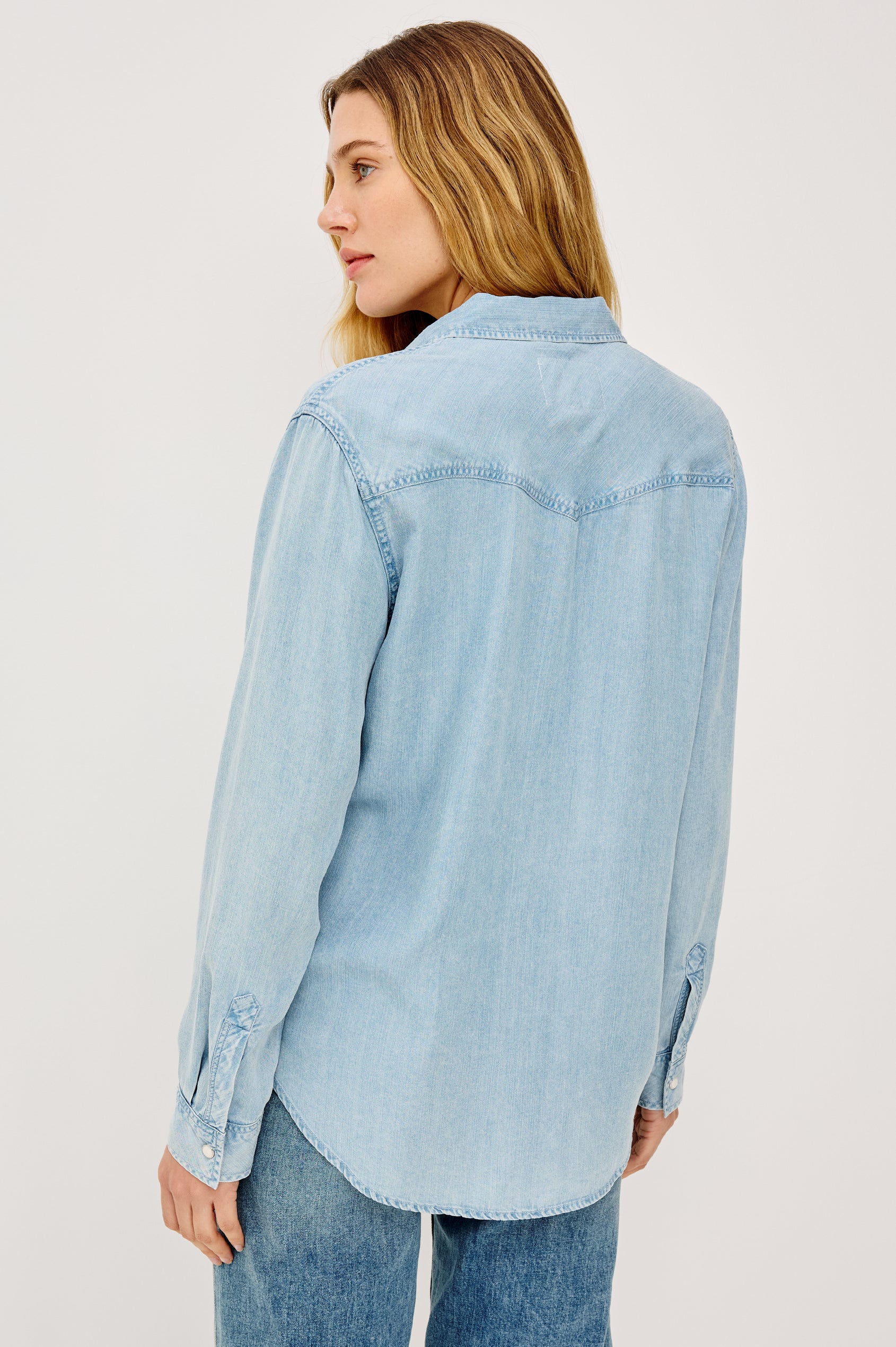Remi is a utility-style Tencel denim shirt with a relaxed fit. The shirt features a notched collar, two front flap pockets, and faux horn buttons etched with a logo in medium indigo colorway - Front View Featured on Model