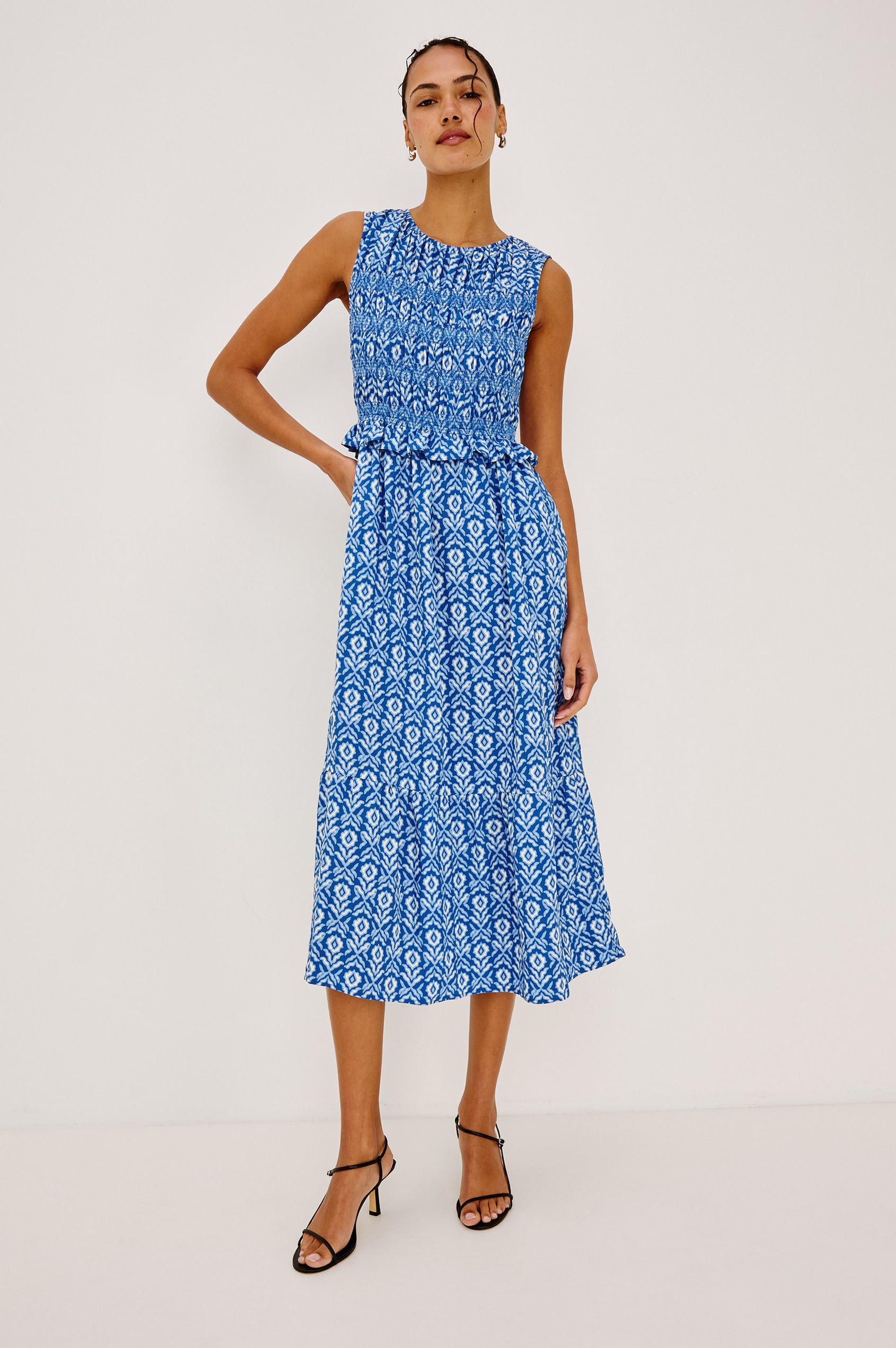 Rialto Midi Dress in Cotton Poplin With High Neckline, Smocked Bodice, Sleeveless Cut, Ruffle Trim, and Tiered Hem in Blue Ikat Colorway - Full Body Front View Featured on Model
