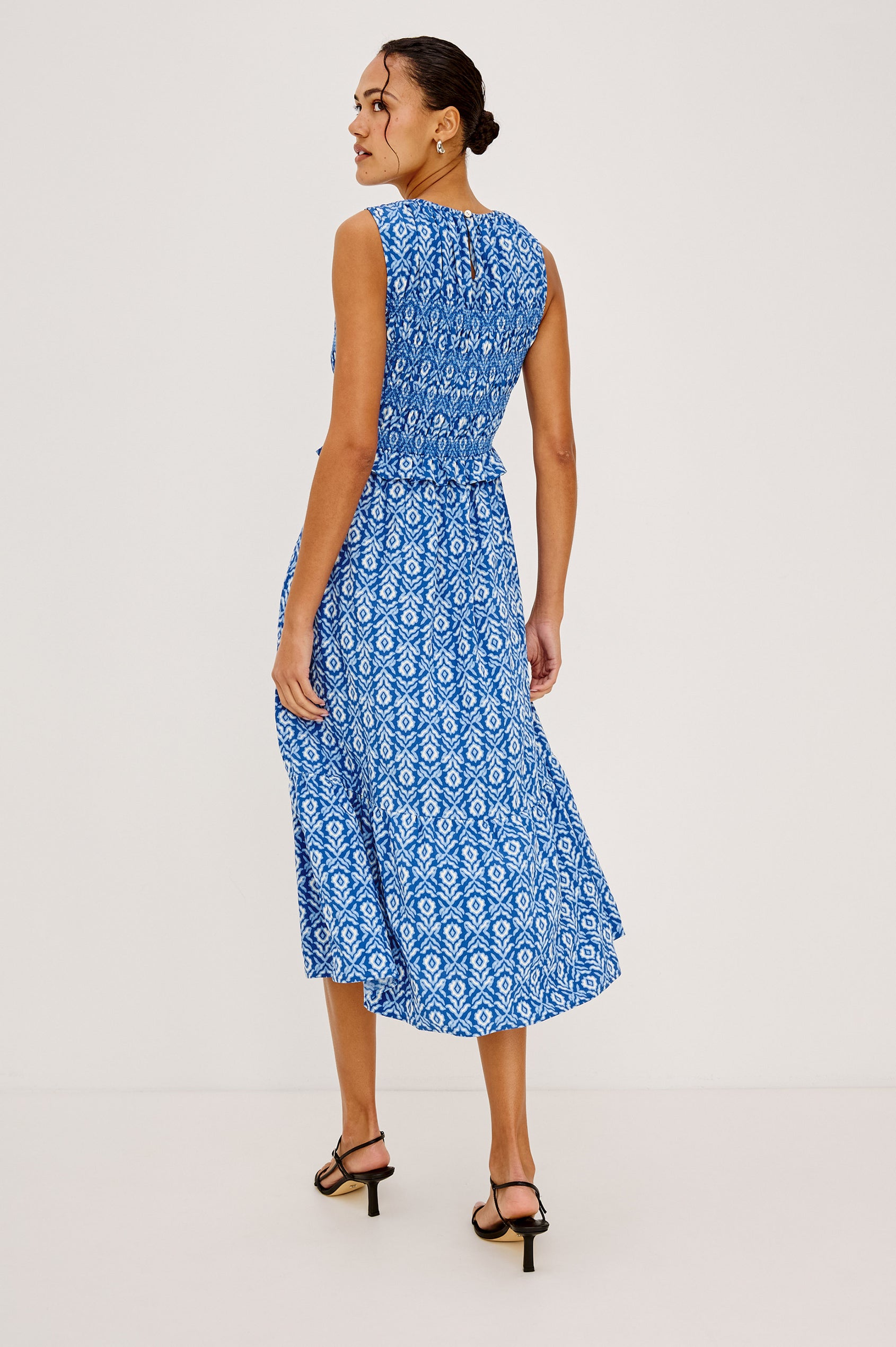 Rialto Midi Dress in Cotton Poplin With High Neckline, Smocked Bodice, Sleeveless Cut, Ruffle Trim, and Tiered Hem in Blue Ikat Colorway - Full Body Back View Featured on Model