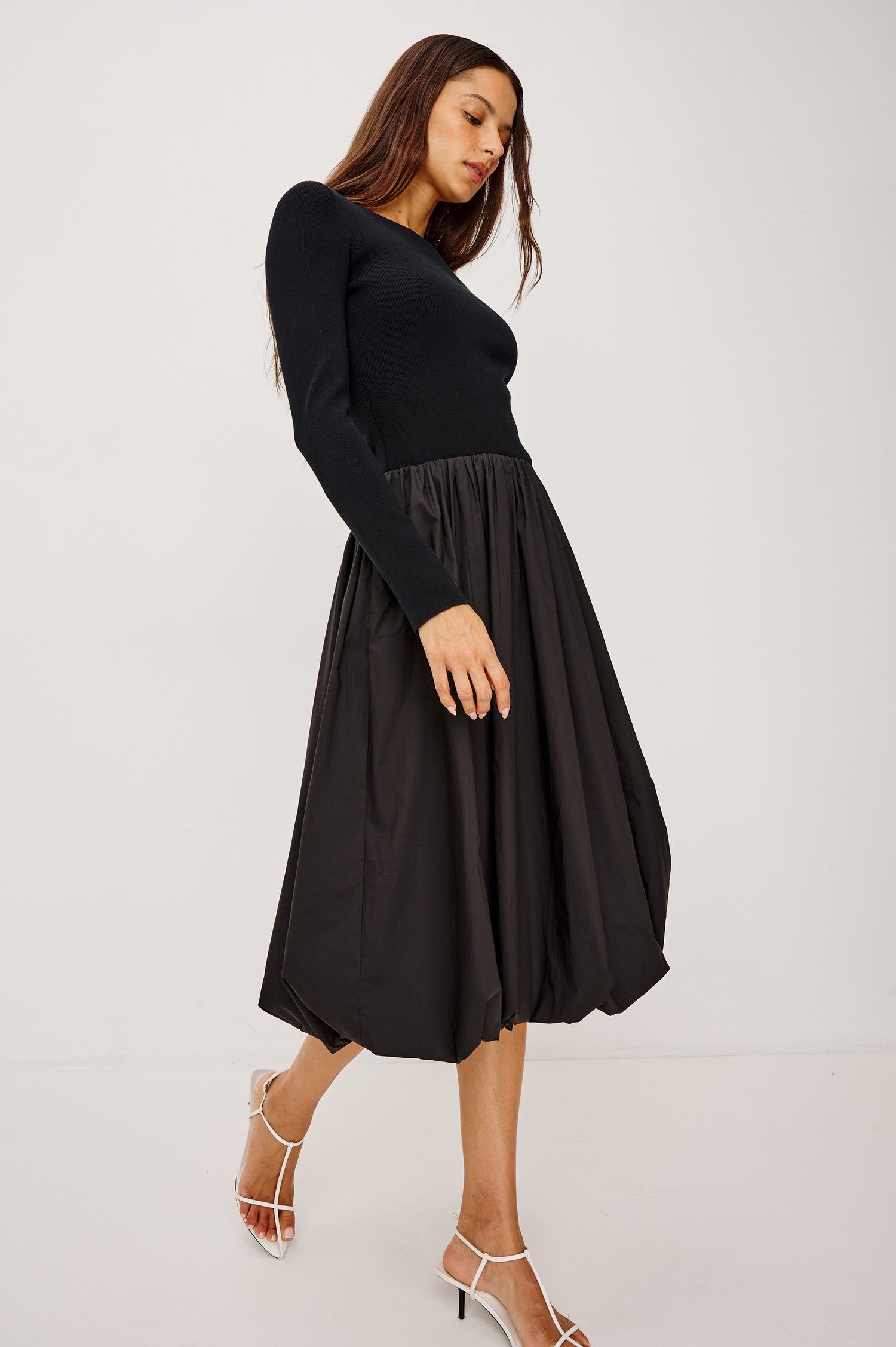 Romana Midi Dress in Fine Gauge Knit and Poplin With Fitted Upper Body, Boat Neckline, Long Sleeves, Drop Waistline, and Voluminous Bubble Skirt in Black Colorway - Full Body Side View Featured on Model Walking