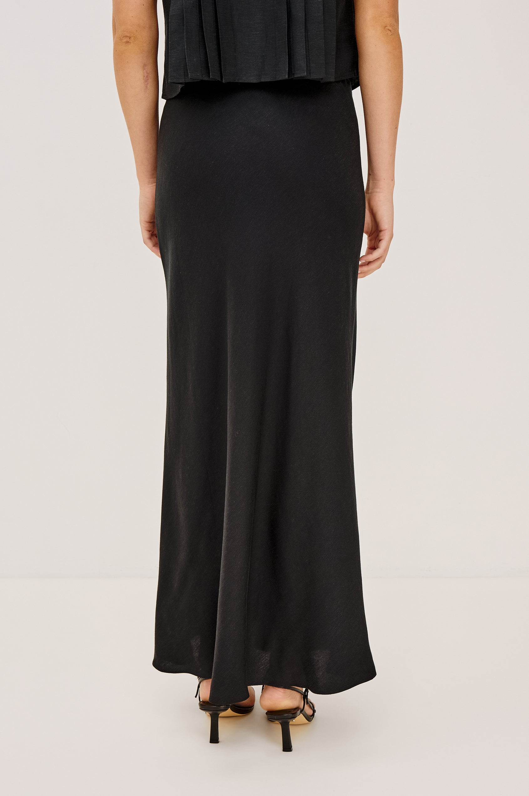 Romina Maxi Skirt in Luxe Linen With High-Waisted Fit and Elastic Waistband in Black Linen Colorway - Lower Body Back View Featured on Model