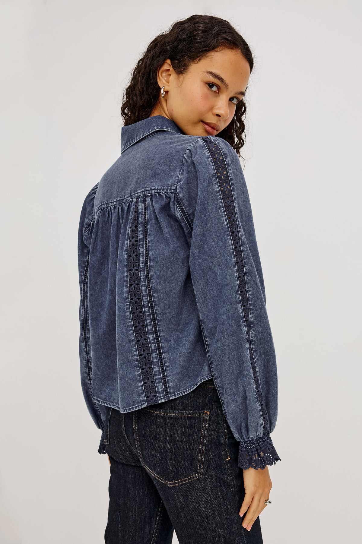 Rowen Shirt in Cotton Chambray With Cropped, Boxy Fit, Front Buttons, Long Puff Sleeves, Contrast Semi-Sheer Eyelet Panels, and Embroidered Trim at Collar and Flared Cuffs in Classic Blue Colorway - Upper Body Back View Featured on Model