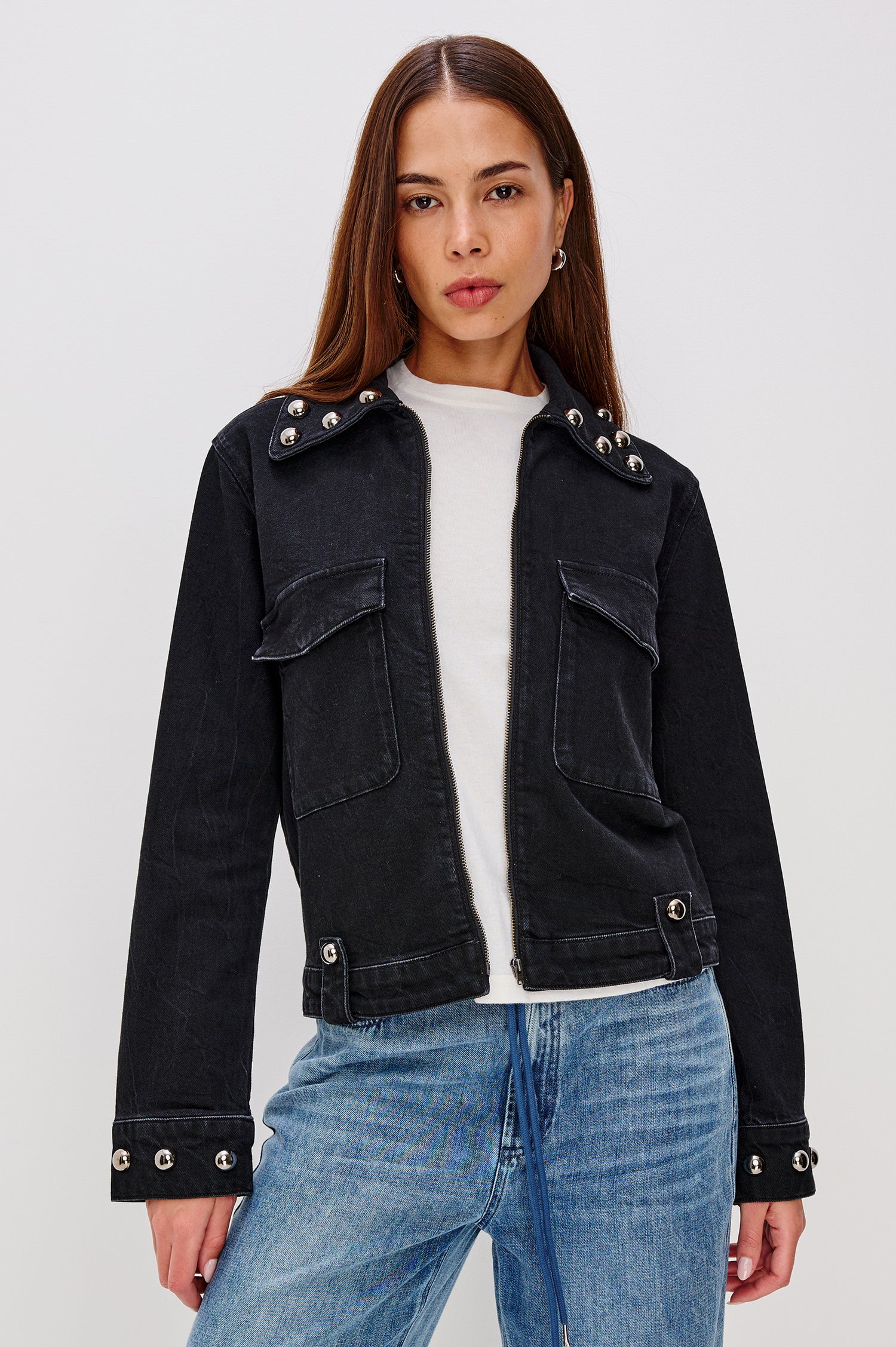 Roxbury Jacket in Denim With Boxy Fit, Nail-Back Studs at Oversized Collar, Long Sleeve Cuffs, and Hem, Oversized Chest Pockets With Hidden Snap Closures, Hem Tabs, and Front Zip in Black Stone Studded Colorway - Upper Body Front View Featured on Model