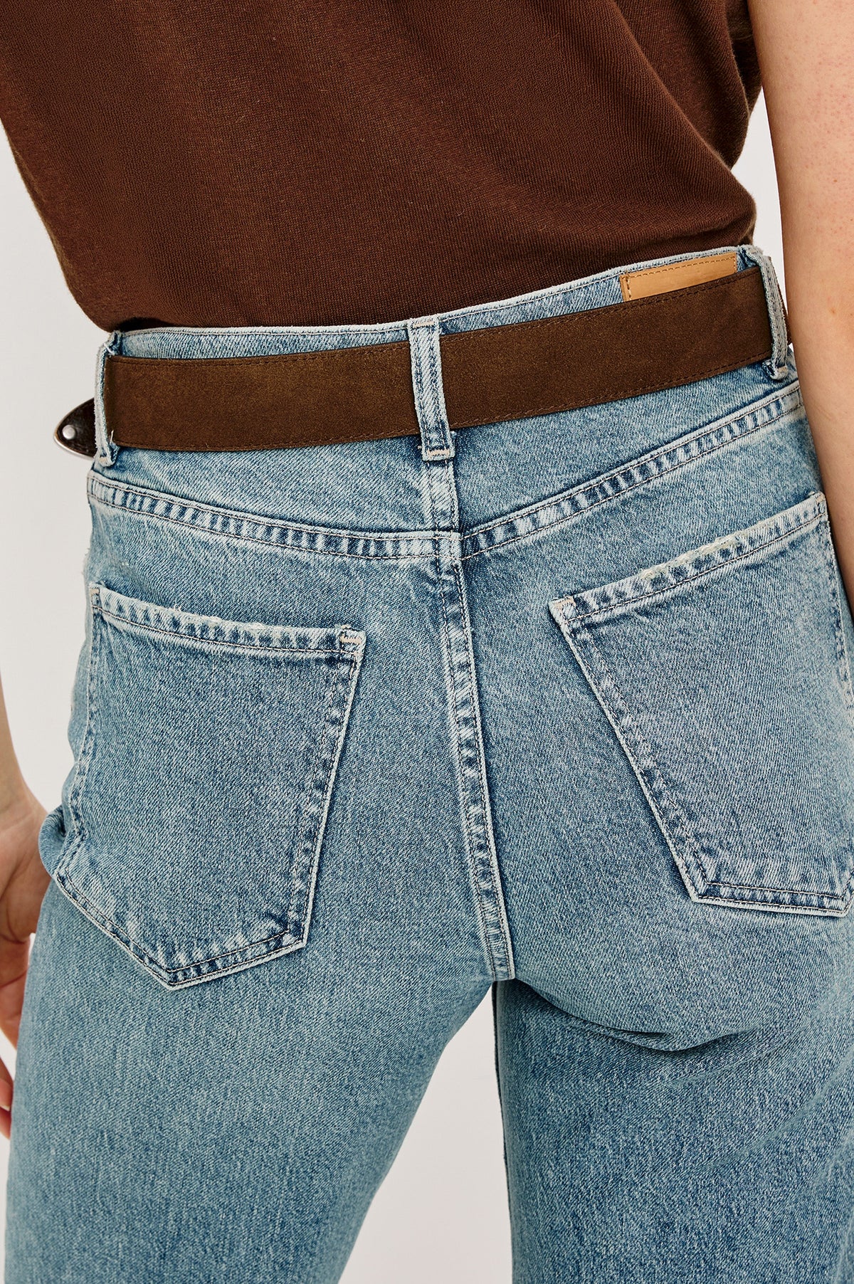 Ryder suede leather belt features silver metal hardware, a metal tip in Chocolate colorway, back close-up view featured on model