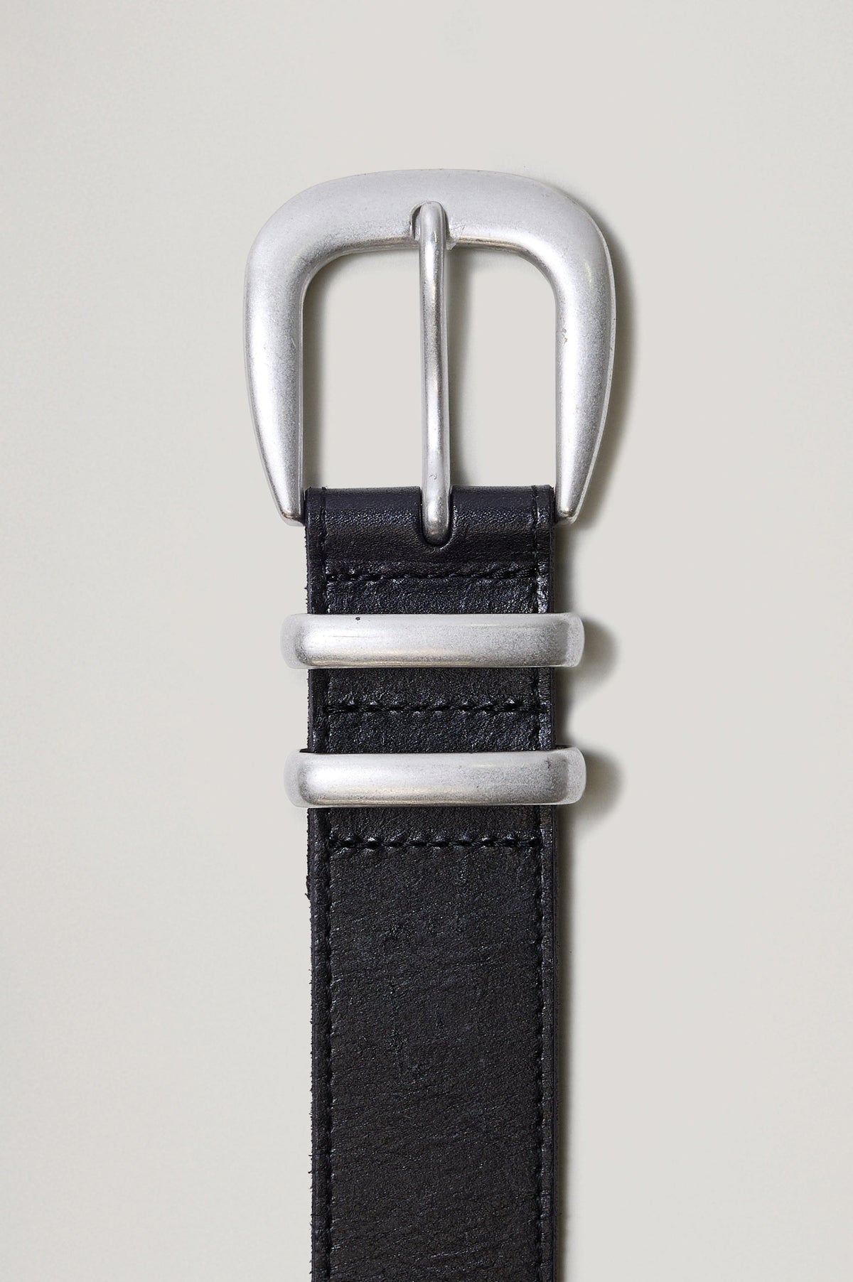 Ryder black leather belt with a brushed silver horseshoe-style buckle, matching dual loops, and a silver metal tip - front view featured on model.