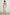 Rylee Sleeveless Ribbed Dress with a Scoop Neck, and a Fringed Asymmetrical Hemline from the Upper Thigh to the Knee in Ecru Colorway - Back Full Body View Featured on Model