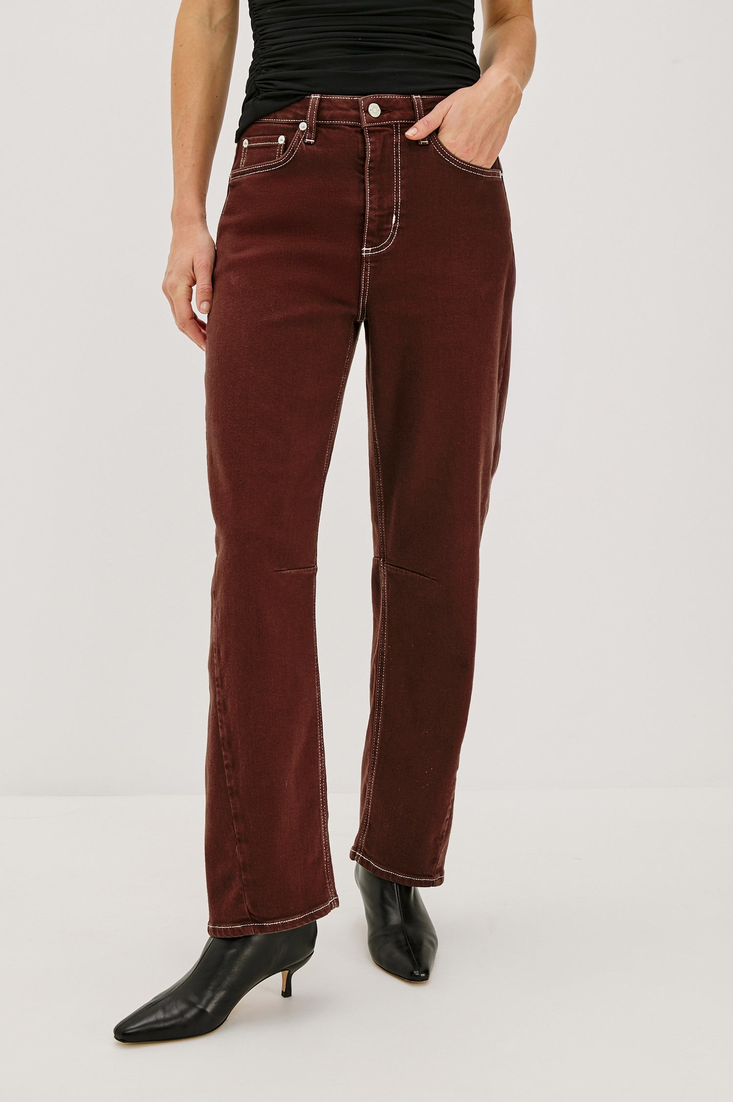 The Samo is a denim barrel leg jean, it features a low-slung fit in light-stretch denim with darting details and a subtle curved seam in Chocolate Contrast Stitch colorway. Front view featured on model.