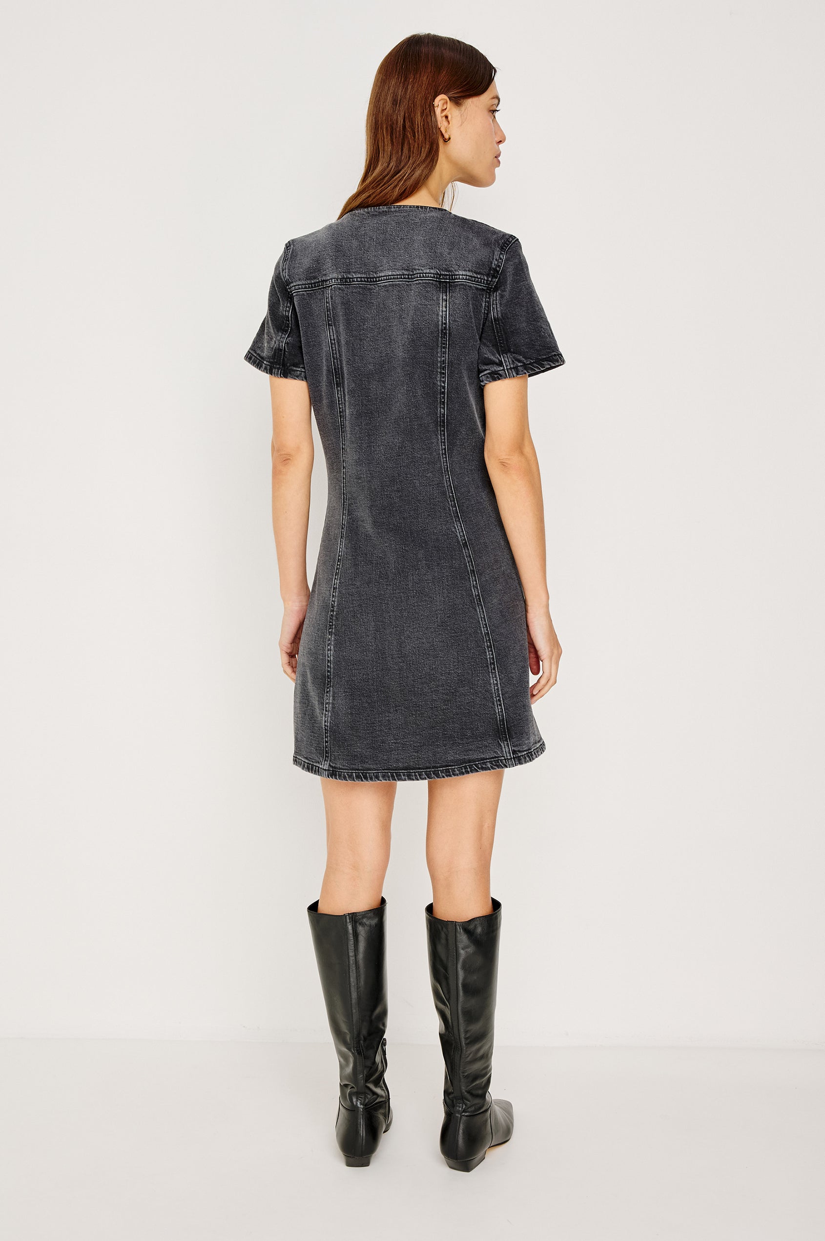 Saratoga Denim Mini Dress With V-Neckline, Buttoned Chest Pockets and Front Buttons, Short Sleeves, Seam DEtails, and A-Line Silhouette in Washed Black Colorway - Full Body Back View Featured on Model