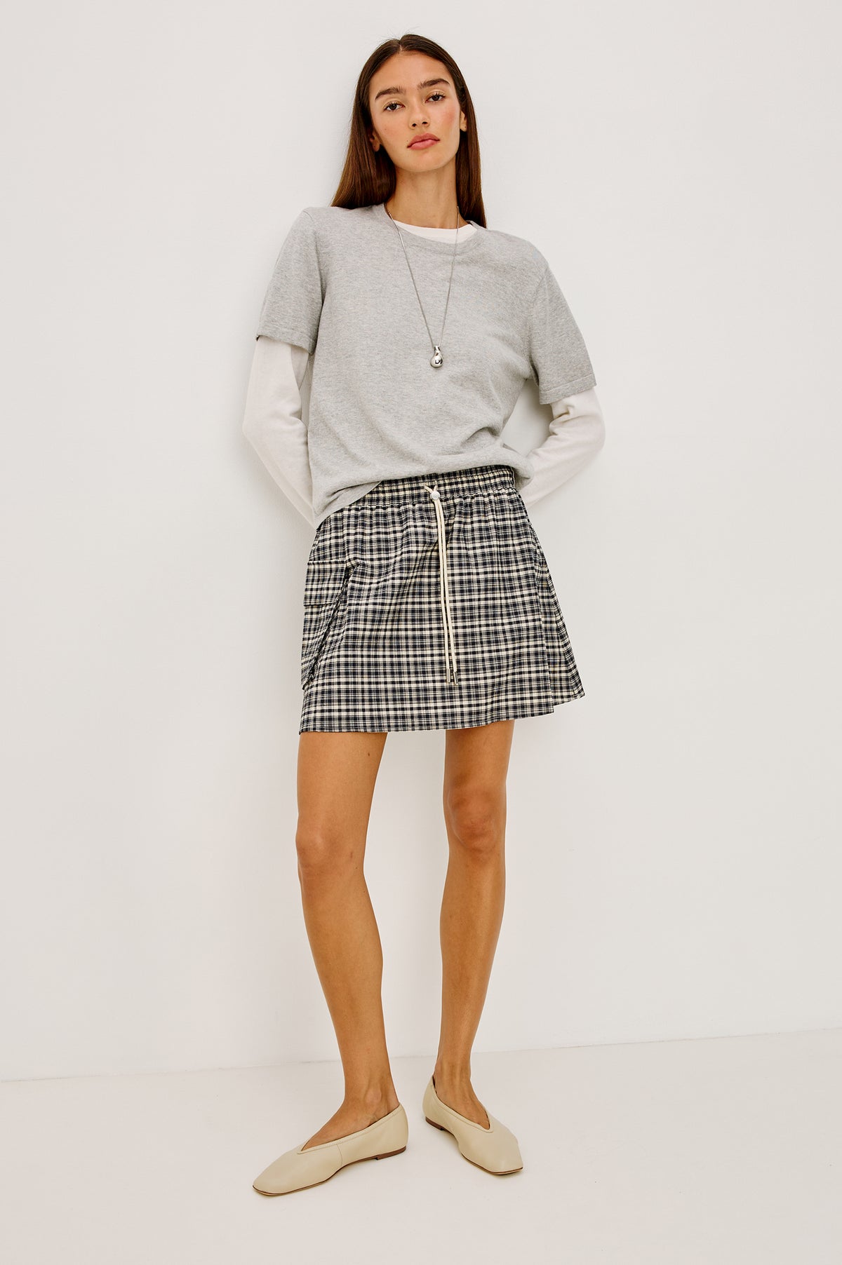 Sayana Mini Skirt in Crinkle Nylon With High-Waisted Fit, Elastic Drawcord Waist, Side Flap Pocket, and Full Lining in Mini Check Colorway - Lower Body Front View Featured on Model