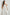 Selani Midi Dress With an Asymmetrical Neckline, Mid-Thigh Slide Slit and Cinched Waistband in White Colorway - Front View Featured on Model