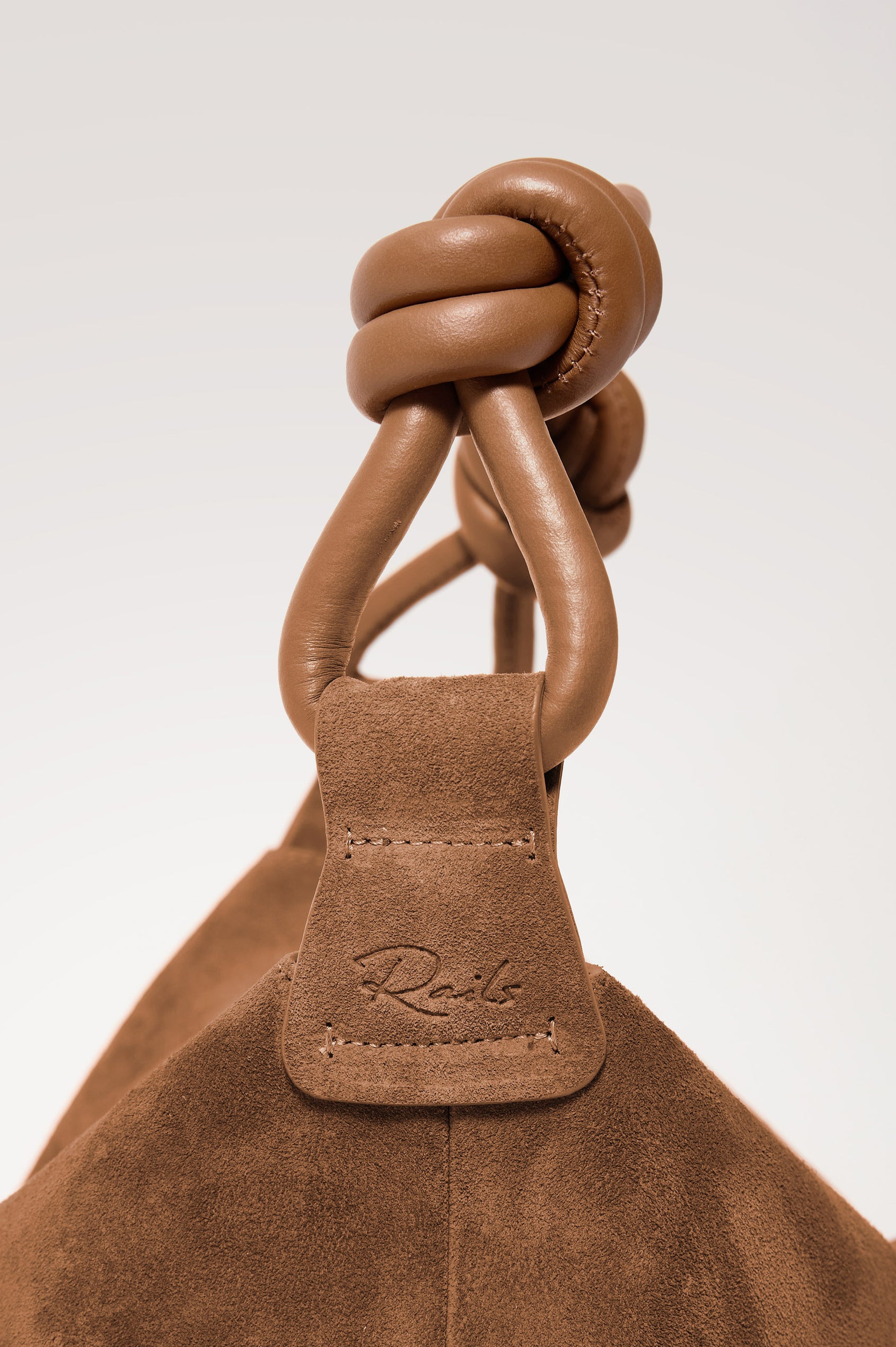 Siena Hobo Bag in Suede With Knotted Top Strap, Zip Closure With Fringe Tassel Pull, Microsuede Lining, Snap-Button Slip Pocket and Foil Logo Stamp at Interior in Camel Suede Colorway - Side Close Up Product View Featured