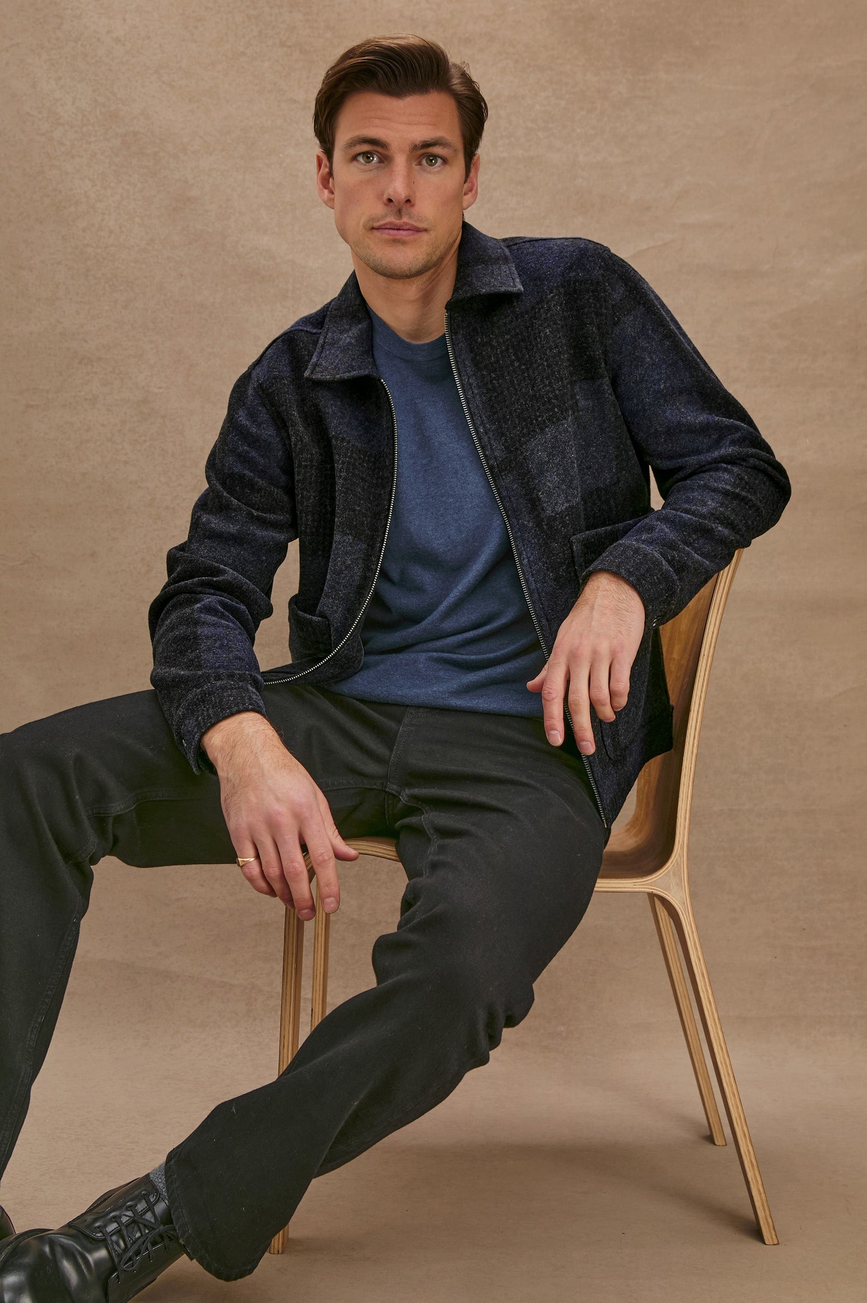 The Simon is a collared zip front jacket with front patch pockets in Black Navy Block colorway. Front seated view featured on model.