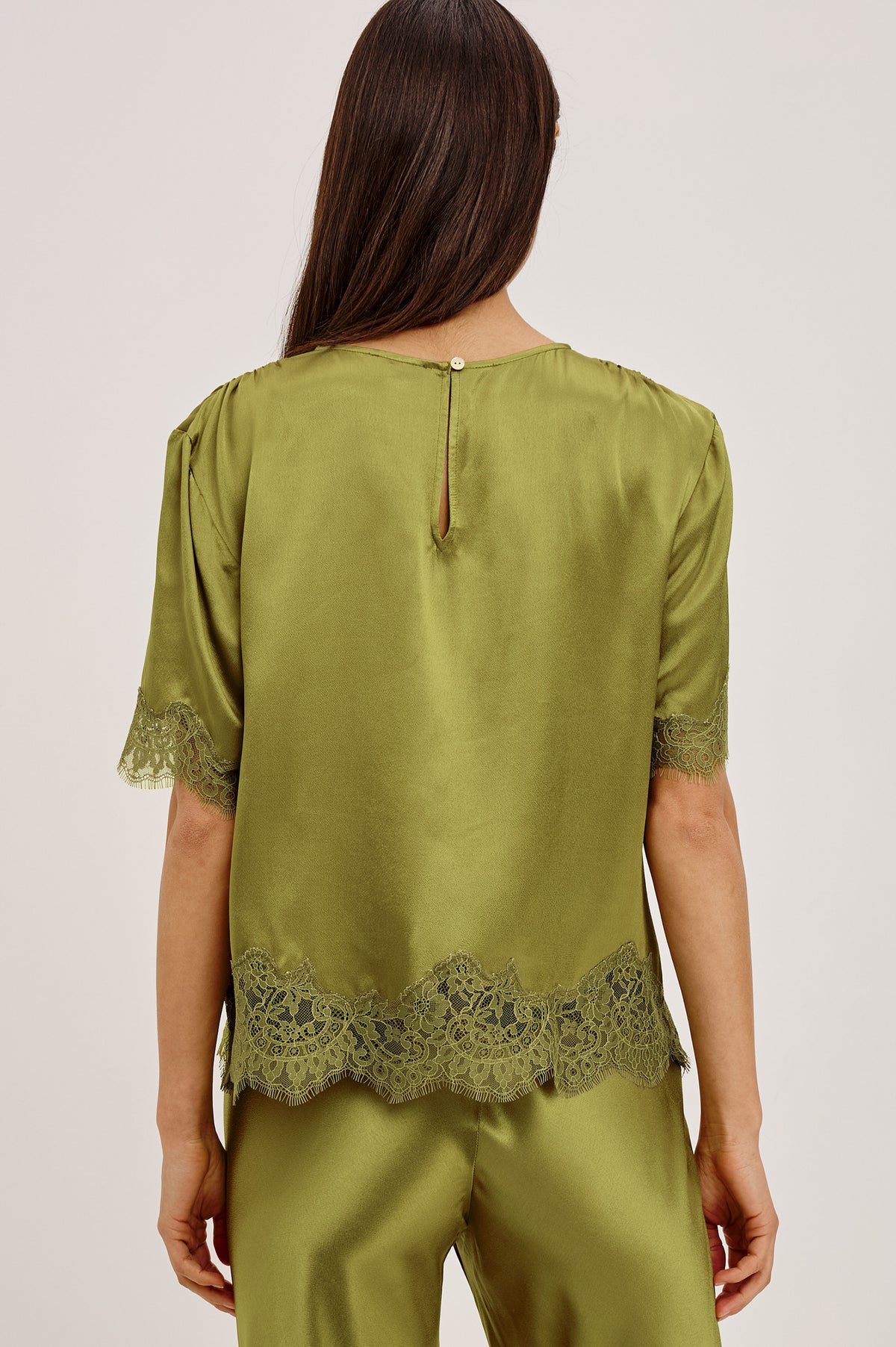 Sonora Shirt in Satin Blend With Loose Boxy Fit, Crew Neck, Shirred Shoulders, Short Sleeves, Button-Loop Back Keyhole, and Lace Trim in Celery ColorwayUpper Body Back View Featured on Model.