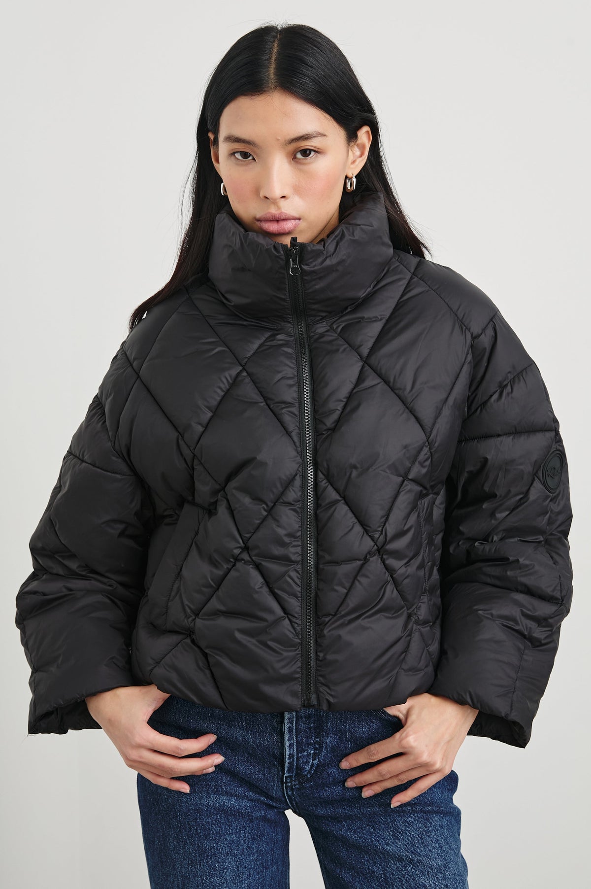 Summit Cropped Puffer Jacket with a Mid-Neck Collar, Two Pockets and a Rails Logo on the Arm in Black Colorway - Front View Featured on Model