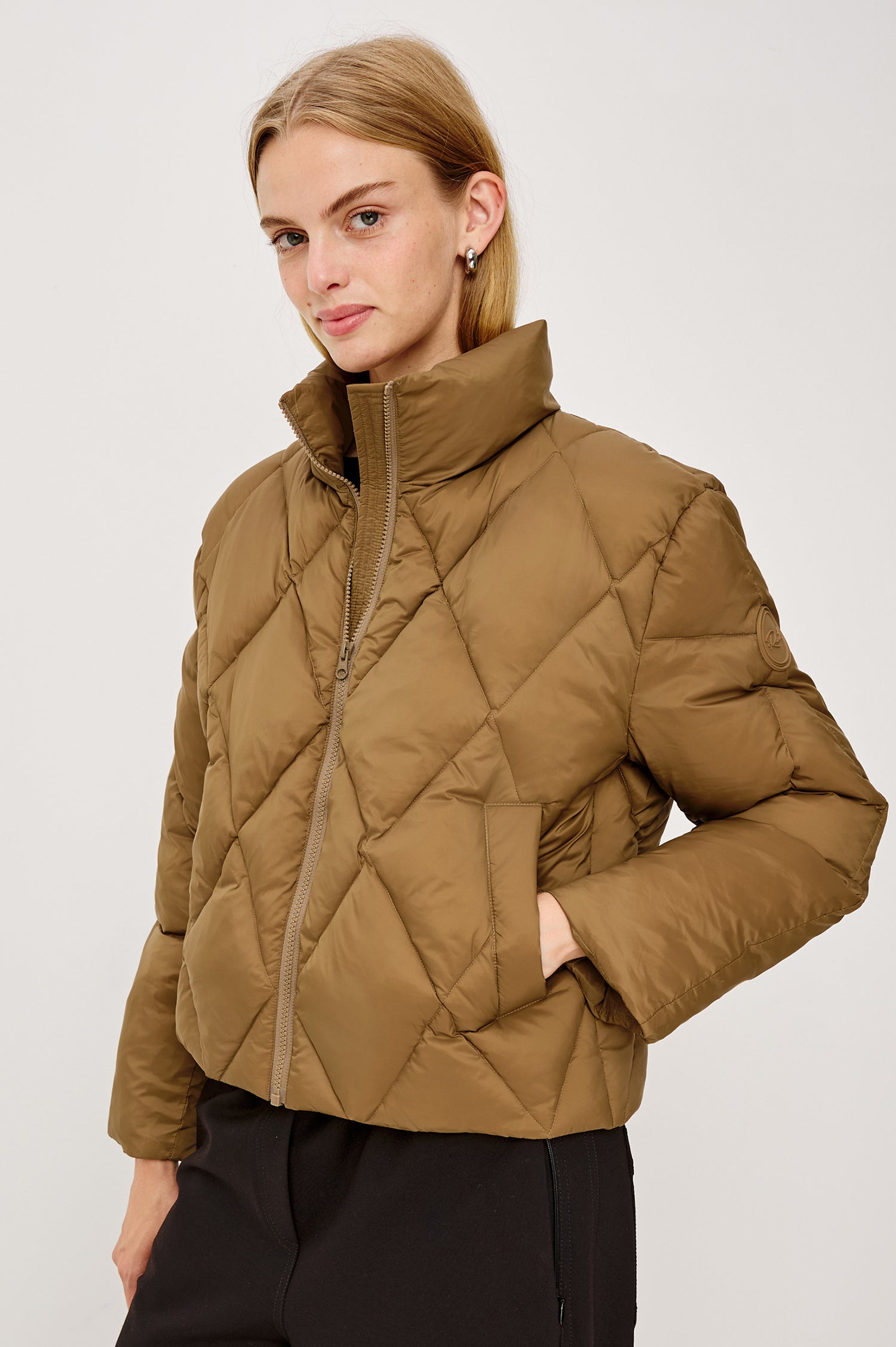 Summit Cropped Puffer Jacket With Stand Collar, Front Zipper, Quilted Detailing, Side Pockets, Tonal Branded Stamp, and Long Sleeves in Ginger Colorway - Upper Body Front View Featured on Model