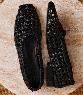 Pair of black woven flats on a textured surface