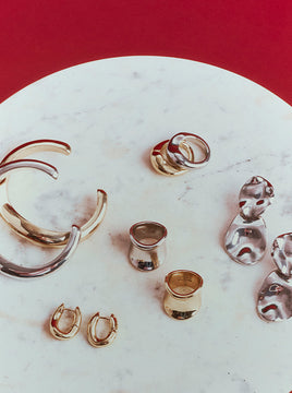 Variety of earrings, rings, and bracelets placed against a textured table.