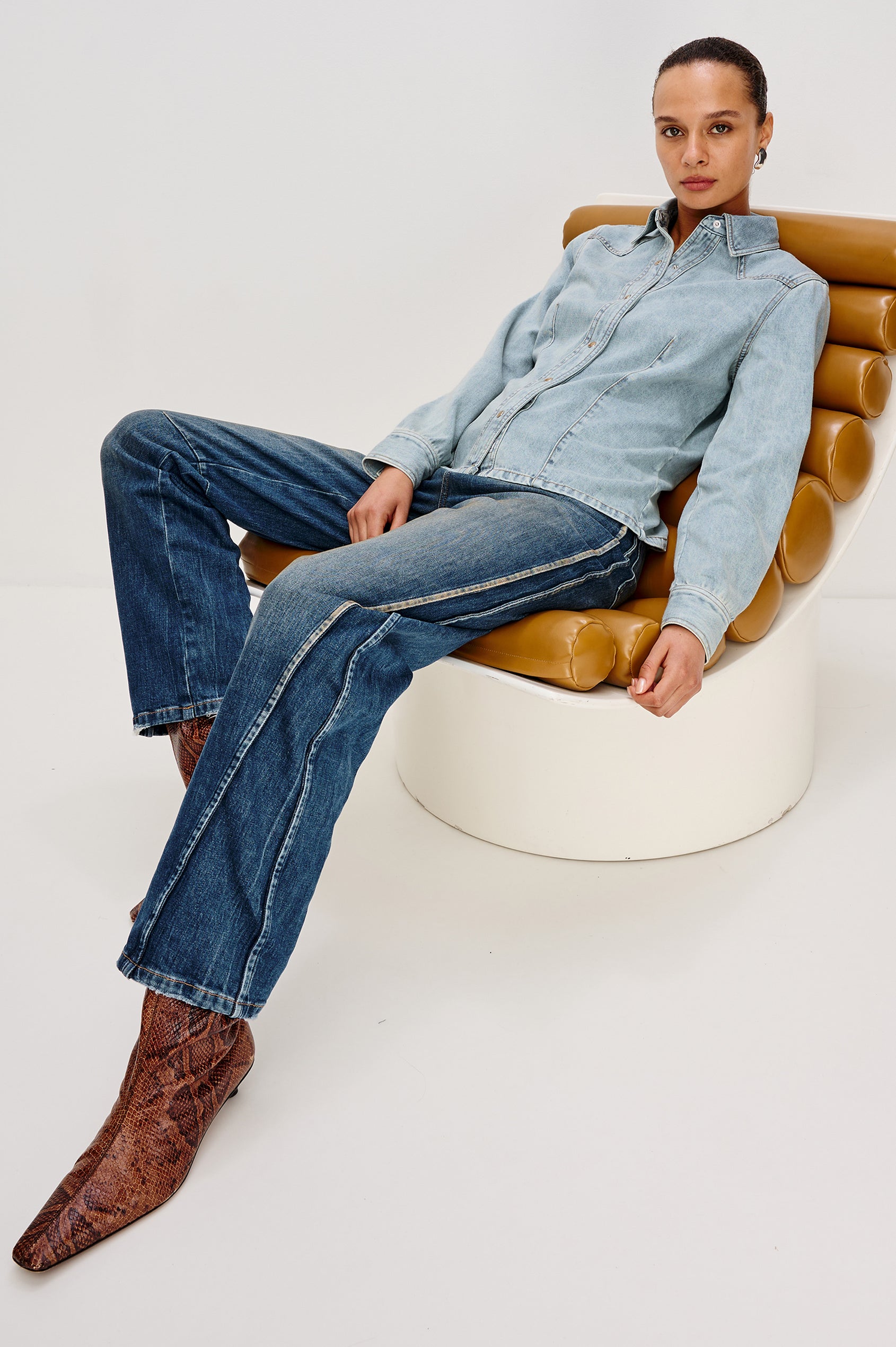 Taiana Cotton Lyocell Denim Shirt in Light Blue Wash With Western Yoke, Front and Back Darts for Fitted Silhouette, Front Pearl Snap Buttons, and Long Sleeves in Bleached Indigo Colorway - Full Body View Featured on Model Sitting
