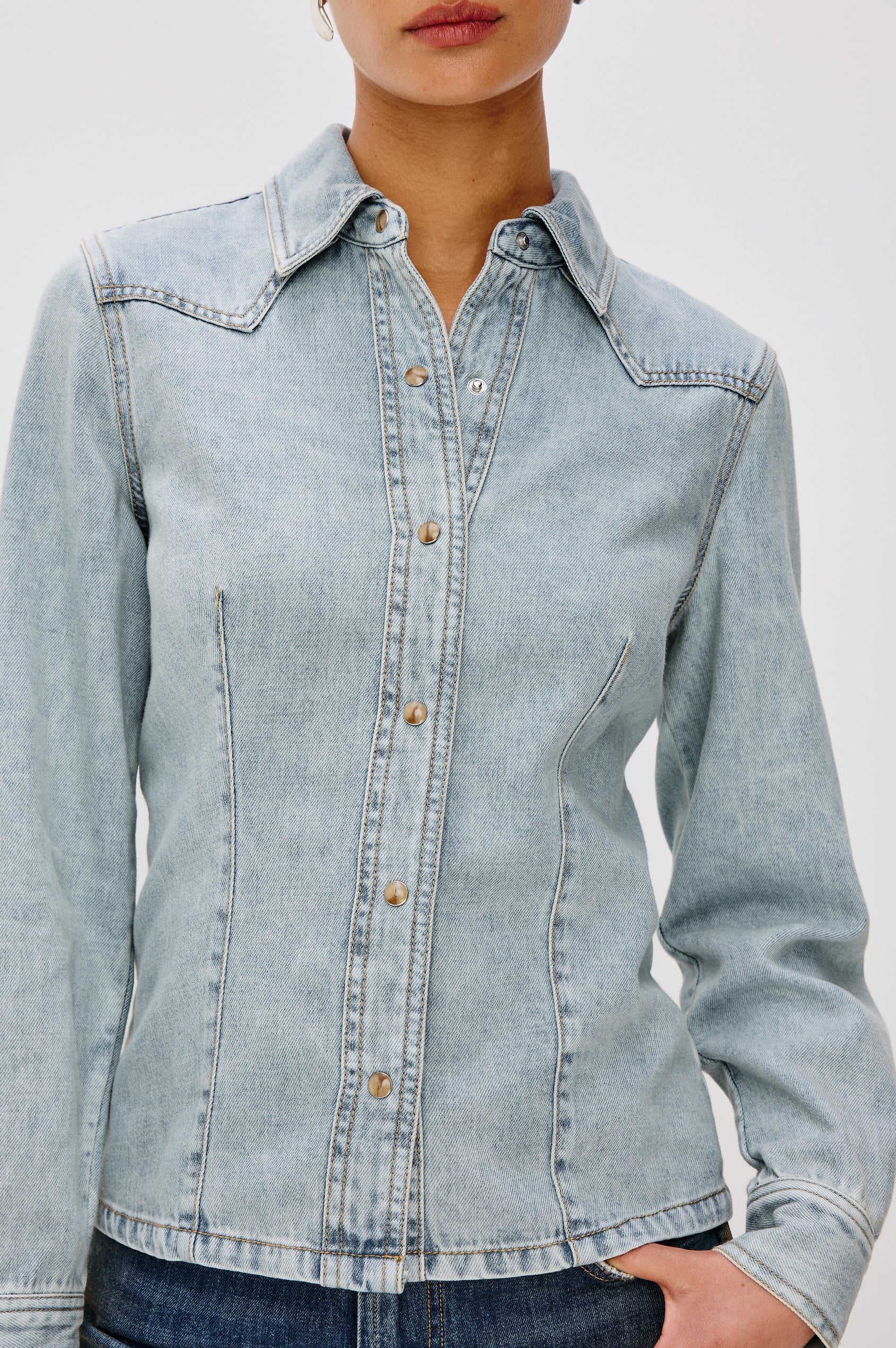 Taiana Cotton Lyocell Denim Shirt in Light Blue Wash With Western Yoke, Front and Back Darts for Fitted Silhouette, Front Pearl Snap Buttons, and Long Sleeves in Bleached Indigo Colorway - Upper Body Close Up View Featured on Model