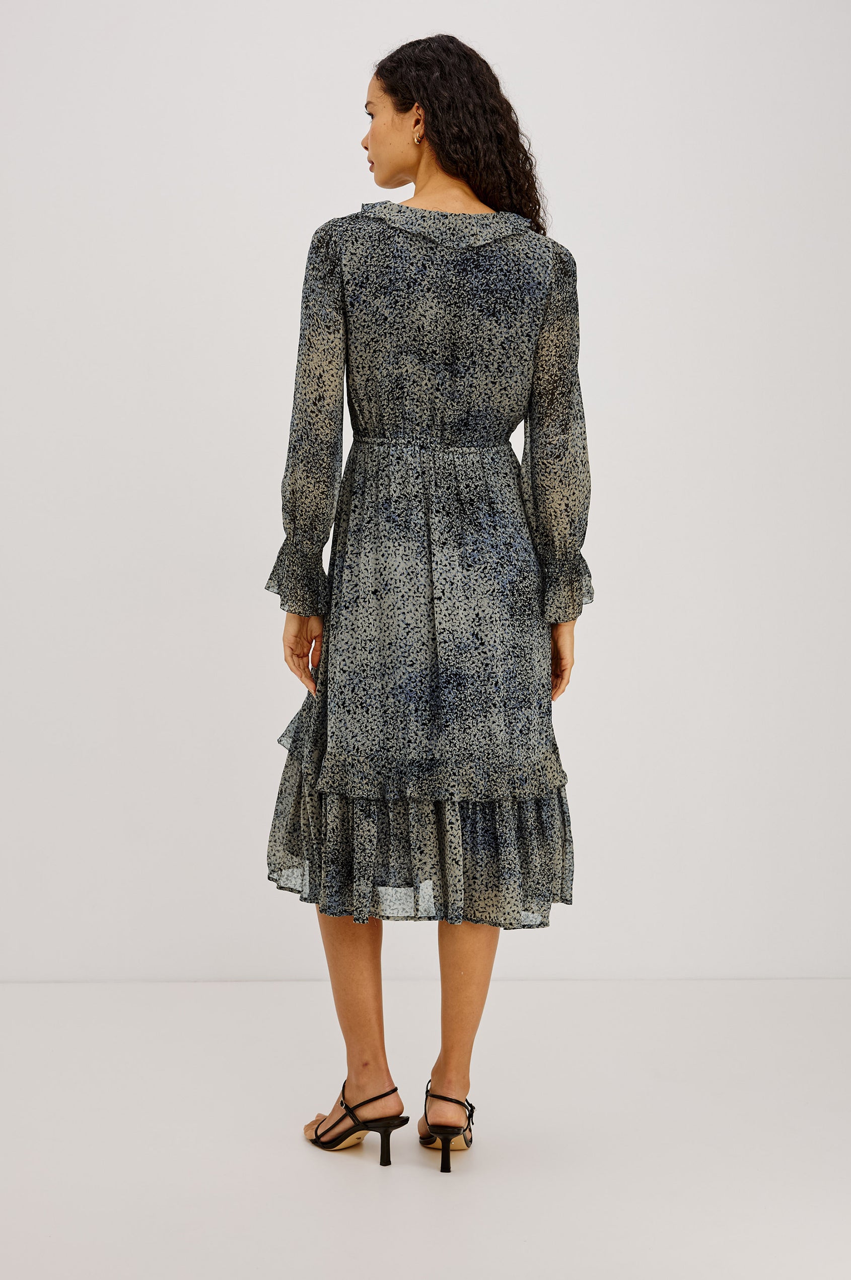Theresa Midi Dress in Chiffon With Lined Body, Ruffle V-Neckline With Ties, Button-Loop Placket, Elastic Drawstring Waist, Long Semi-Sheer Bishop Sleeves, and Asymmetric Tier at Skirt in Agate Colorway - Full Body Back View Featured on Model