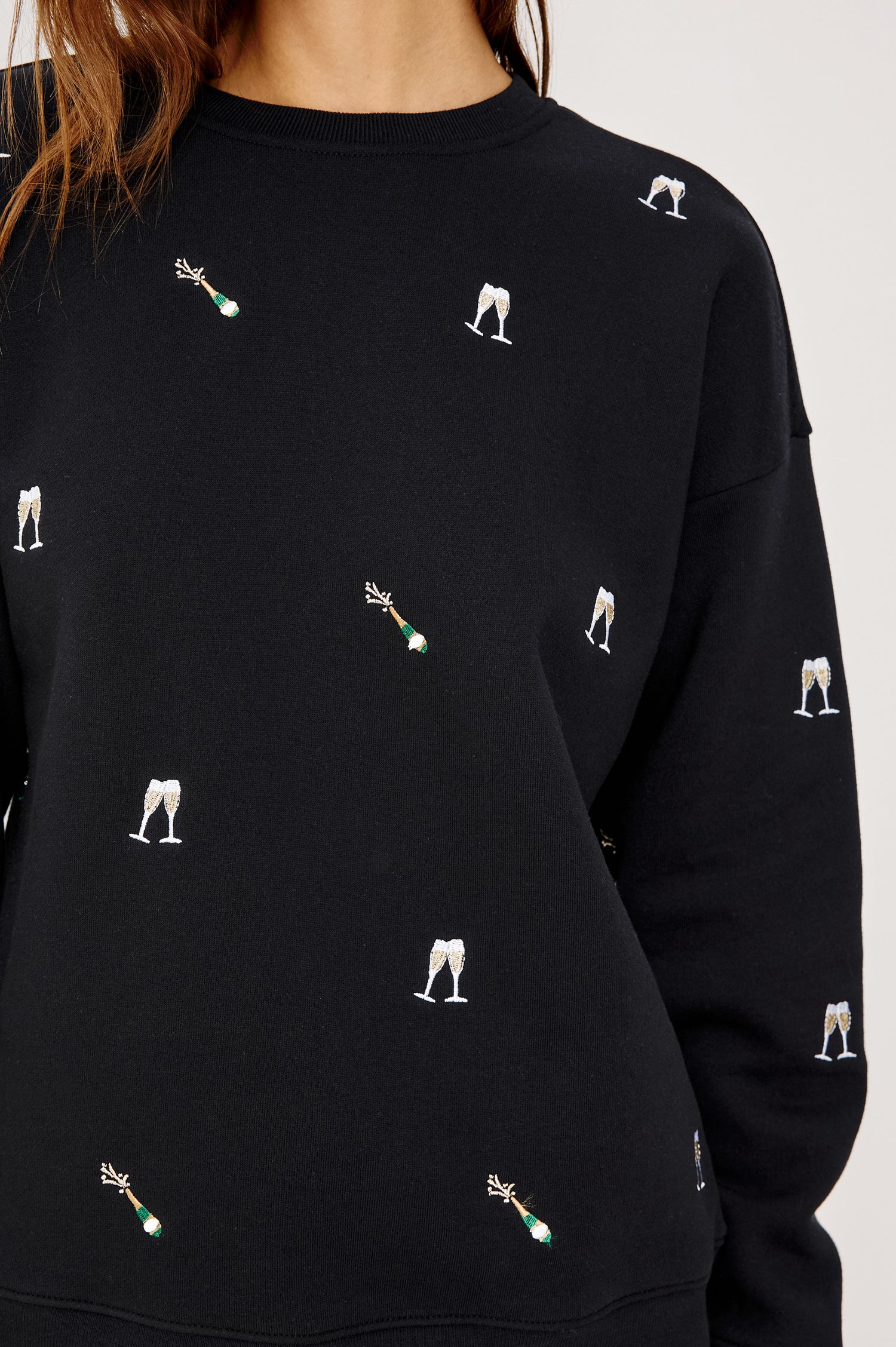 Ramona Crewneck Sweatshirt in Cotton Fleece With Embroidered Champagne Glasses, Dropped Shoulders, Long Sleeves, and Ribbed Trim in Black Champagne Embroidery Colorway - Upper Body Close Up Front View Featured on Model